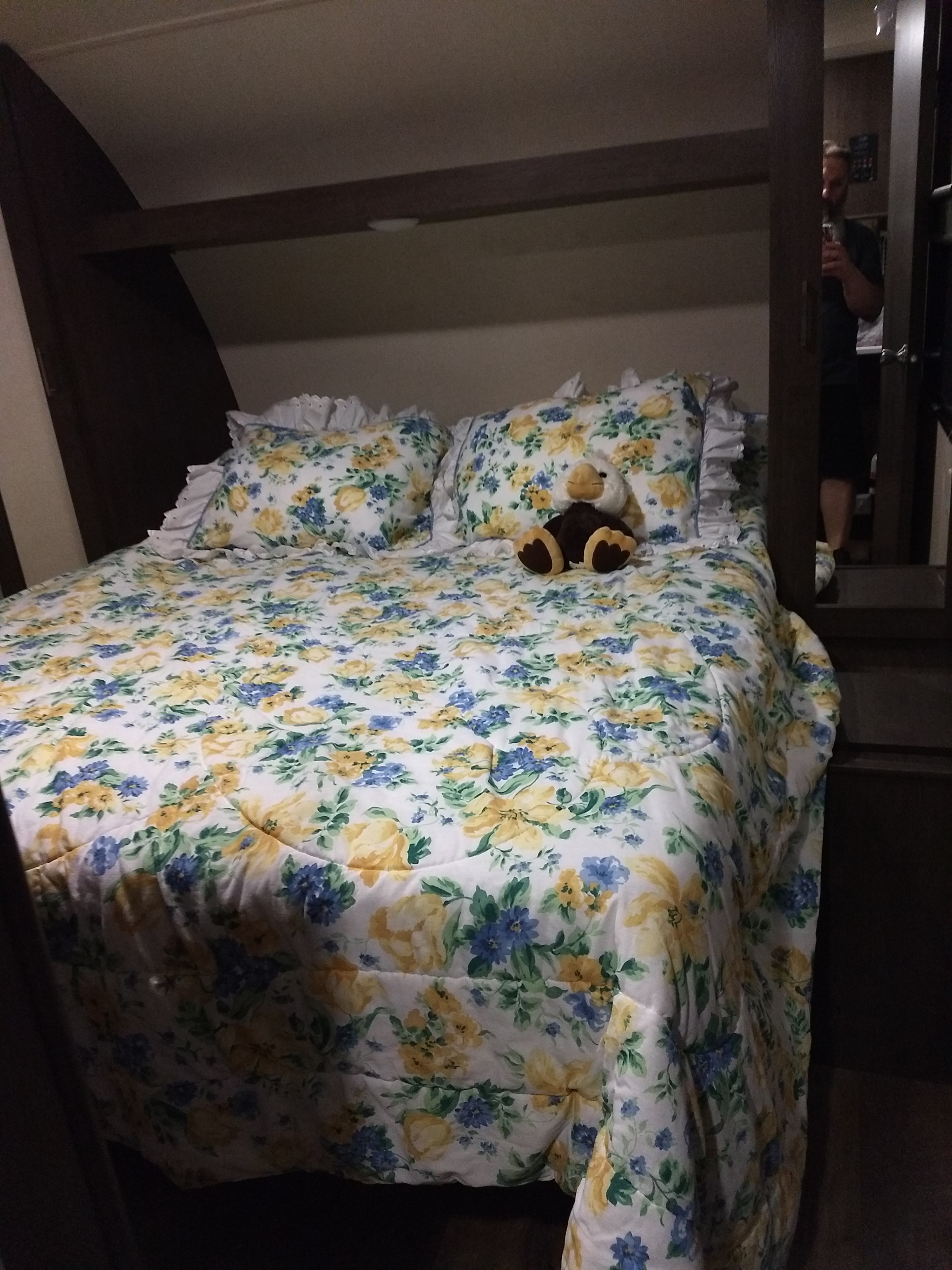 Relax in this RV rental's cozy bedroom. Features floral bedding with yellow & blue flowers, and a cute plush toy.. Forest River Salem 2018