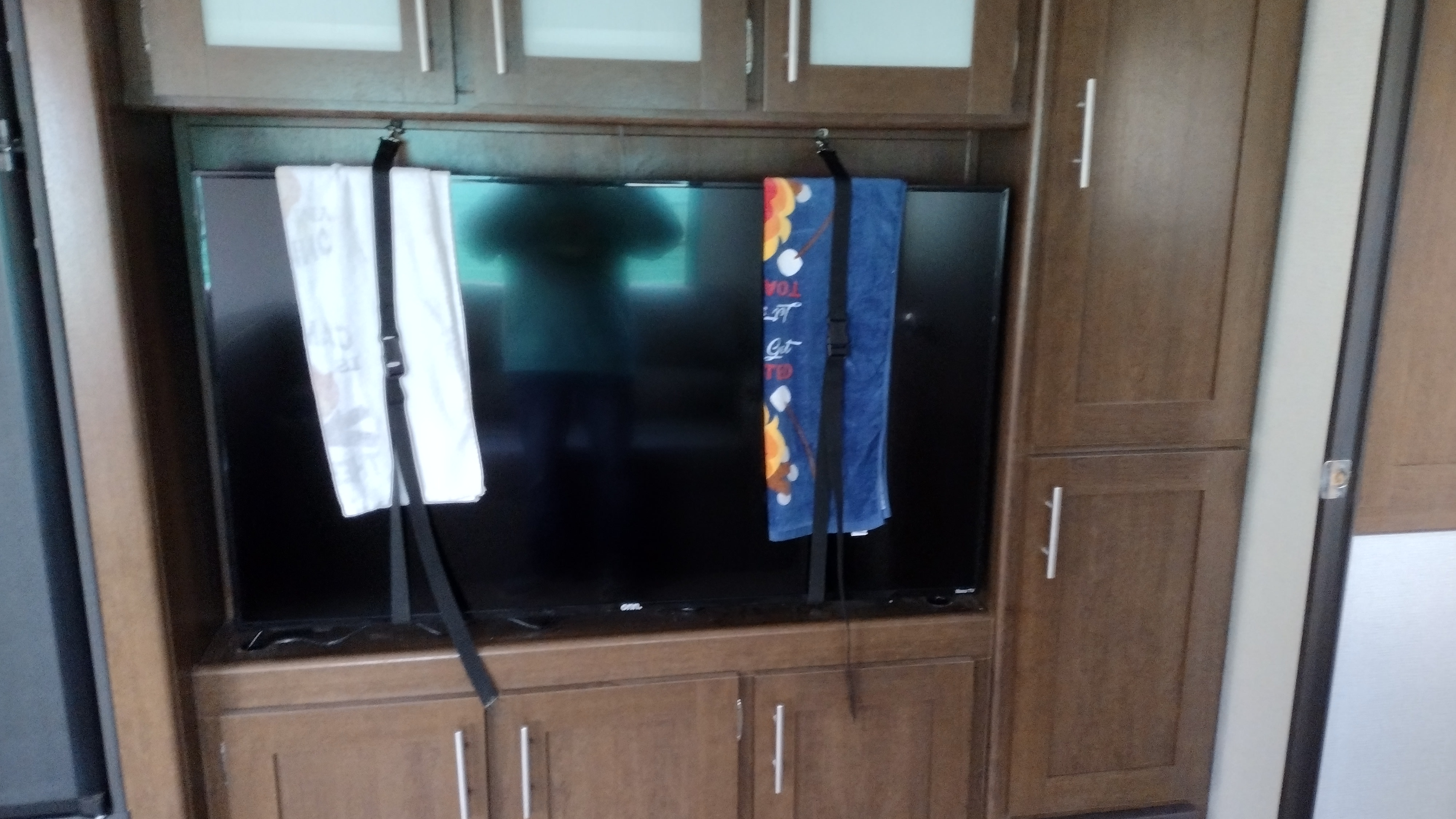 RV rental interior: TV secured for travel by hanging towels and straps within built-in wooden cabinets.. Avenger ATI 2019