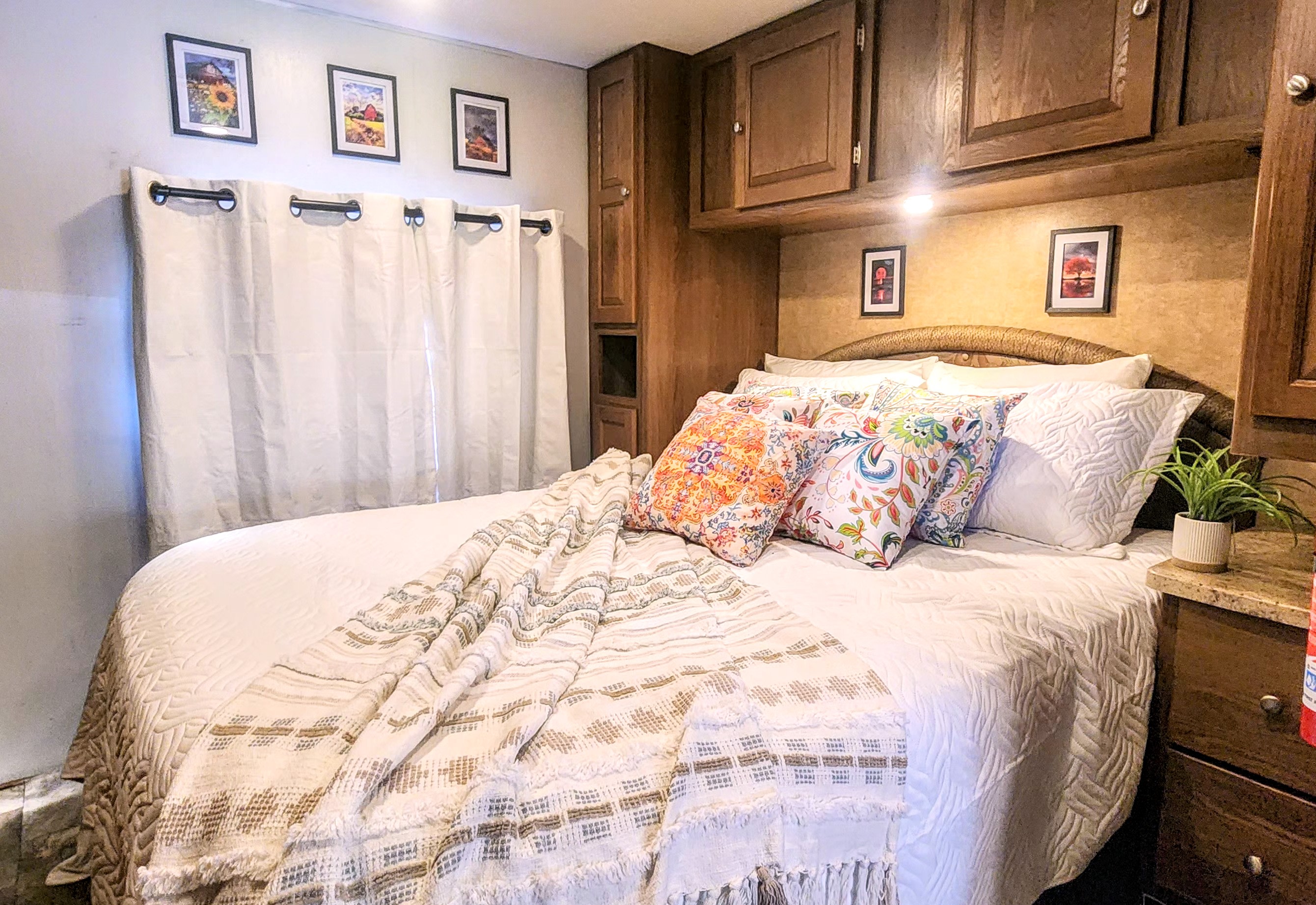 Cozy RV rental bedroom with a large bed, colorful pillows, throw blanket, wall art, and built-in storage.. Forest River Coachmen Leprechaun 2015