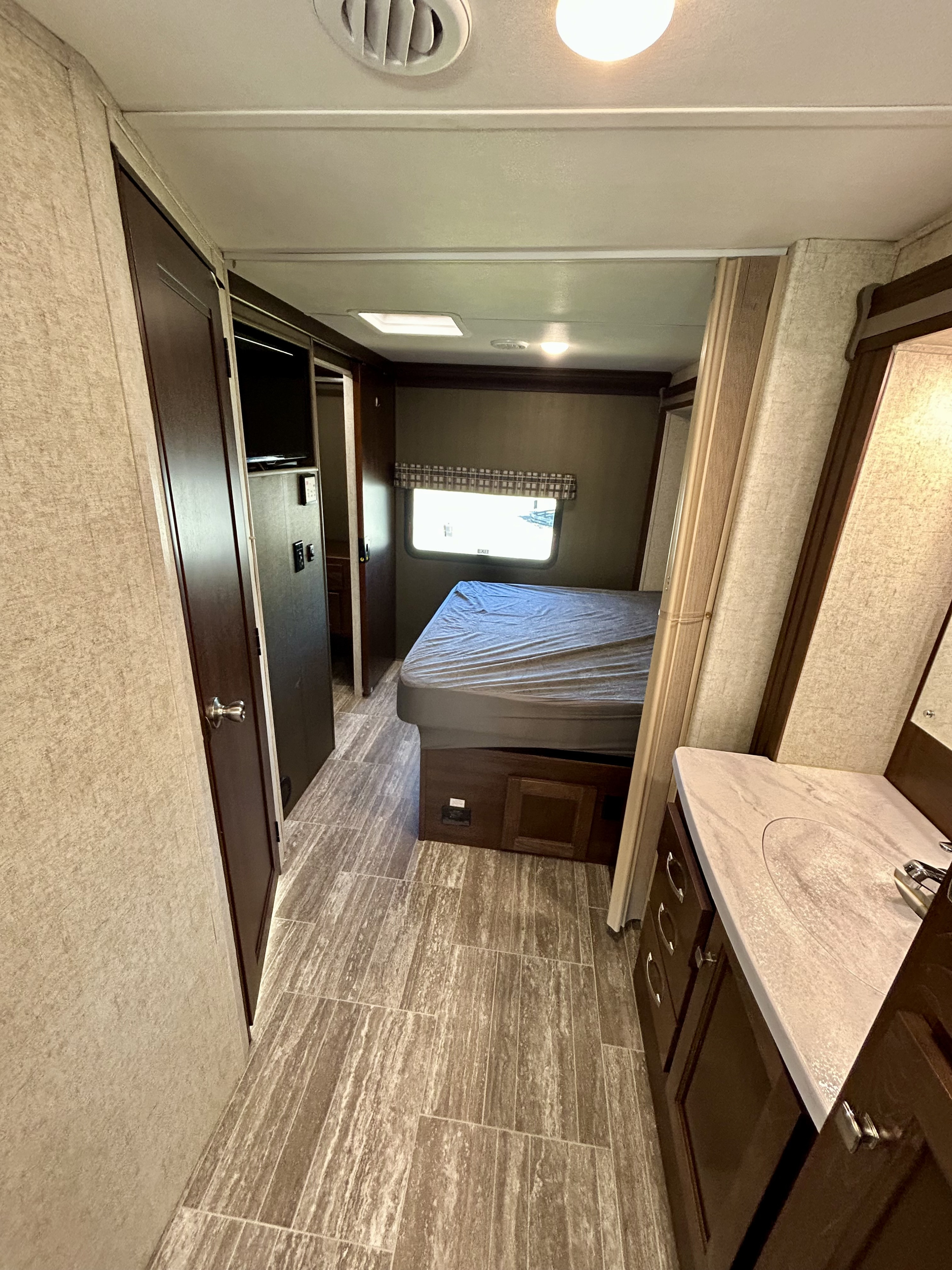 Step inside this rv rental's bedroom and bathroom area, featuring a bed, vanity, and closet space.. Forest River Sunseeker 2020