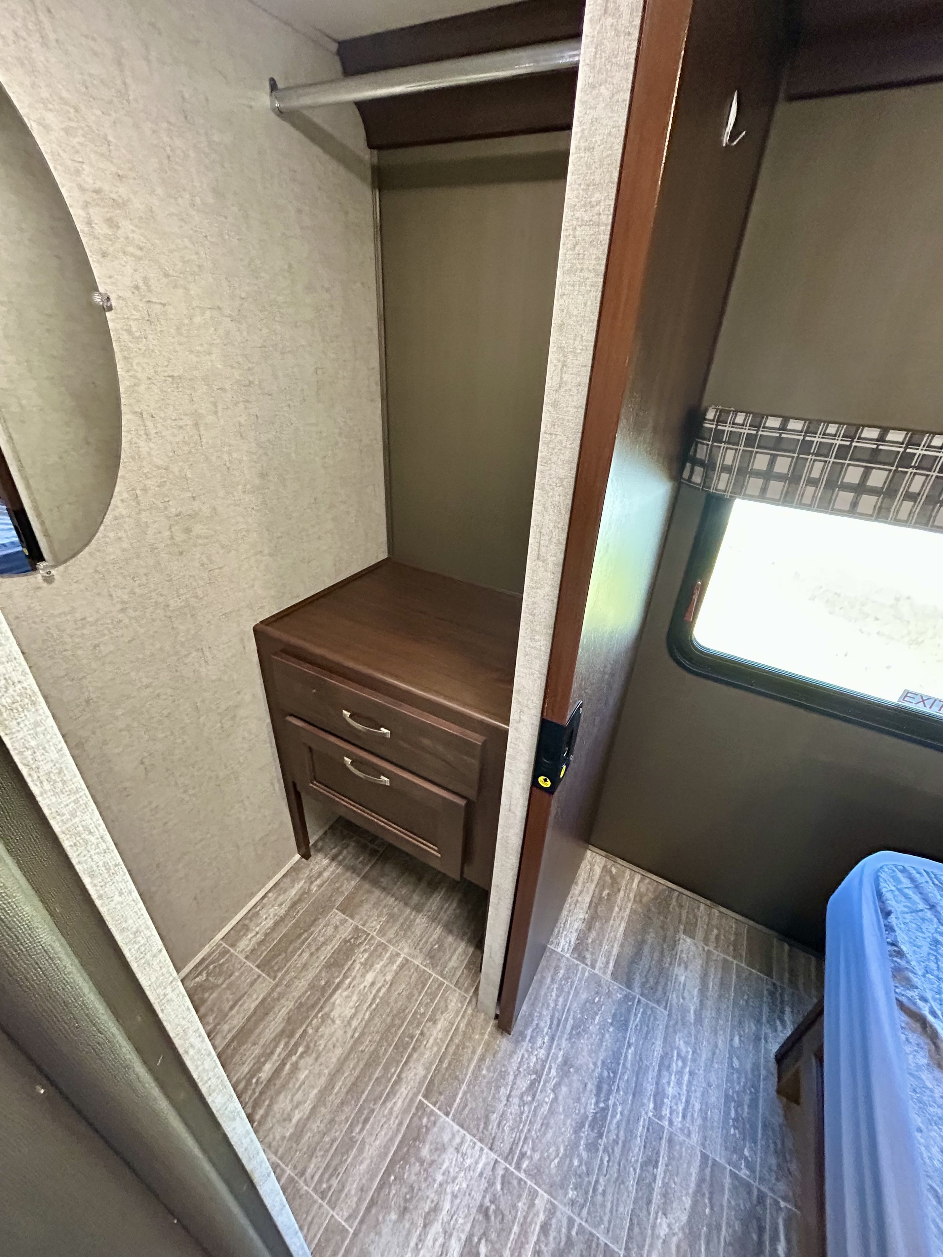 RV rental interior: compact wardrobe featuring a hanging rod, built-in dresser, and wall mirror.. Forest River Sunseeker 2020
