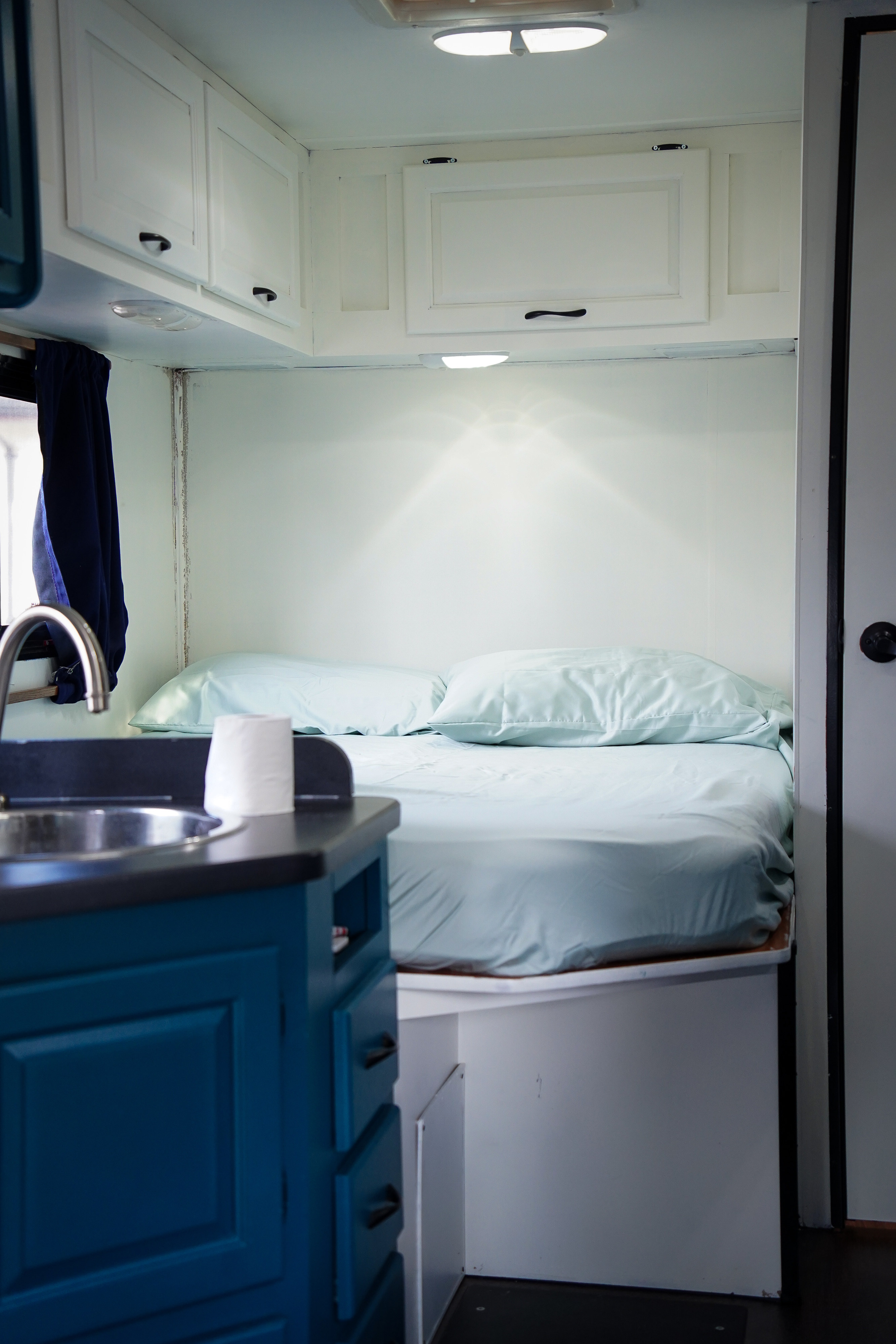 This RV rental offers a cozy interior with a comfy bed, blue sheets, bright lighting, and a functional kitchen area with a sink.. Thor Majestic 2014