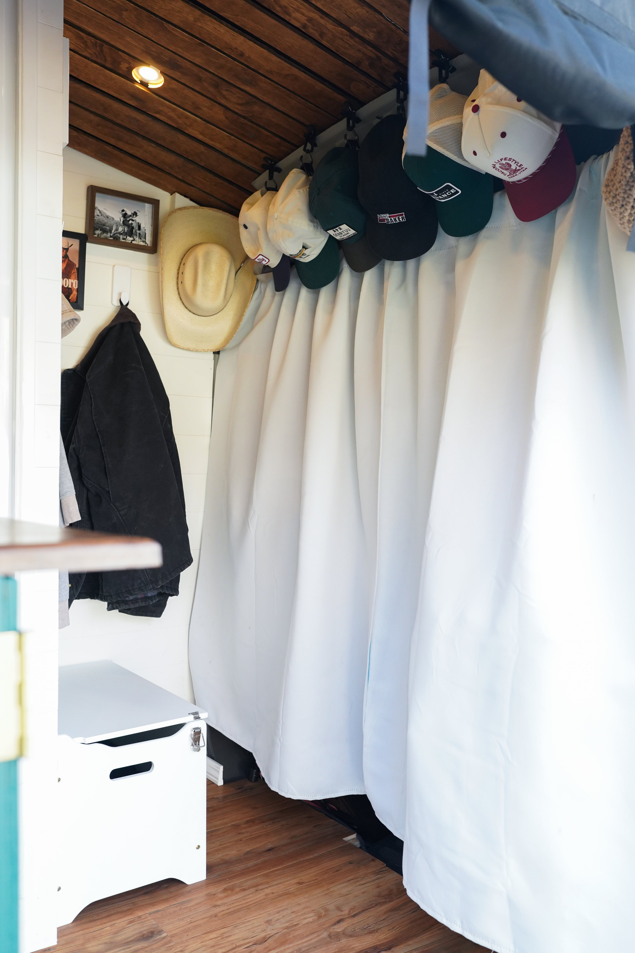 Cozy RV rental interior shows wooden ceiling, white walls, storage bench, and organized hats and jackets.. Ford Transit Custom 2022