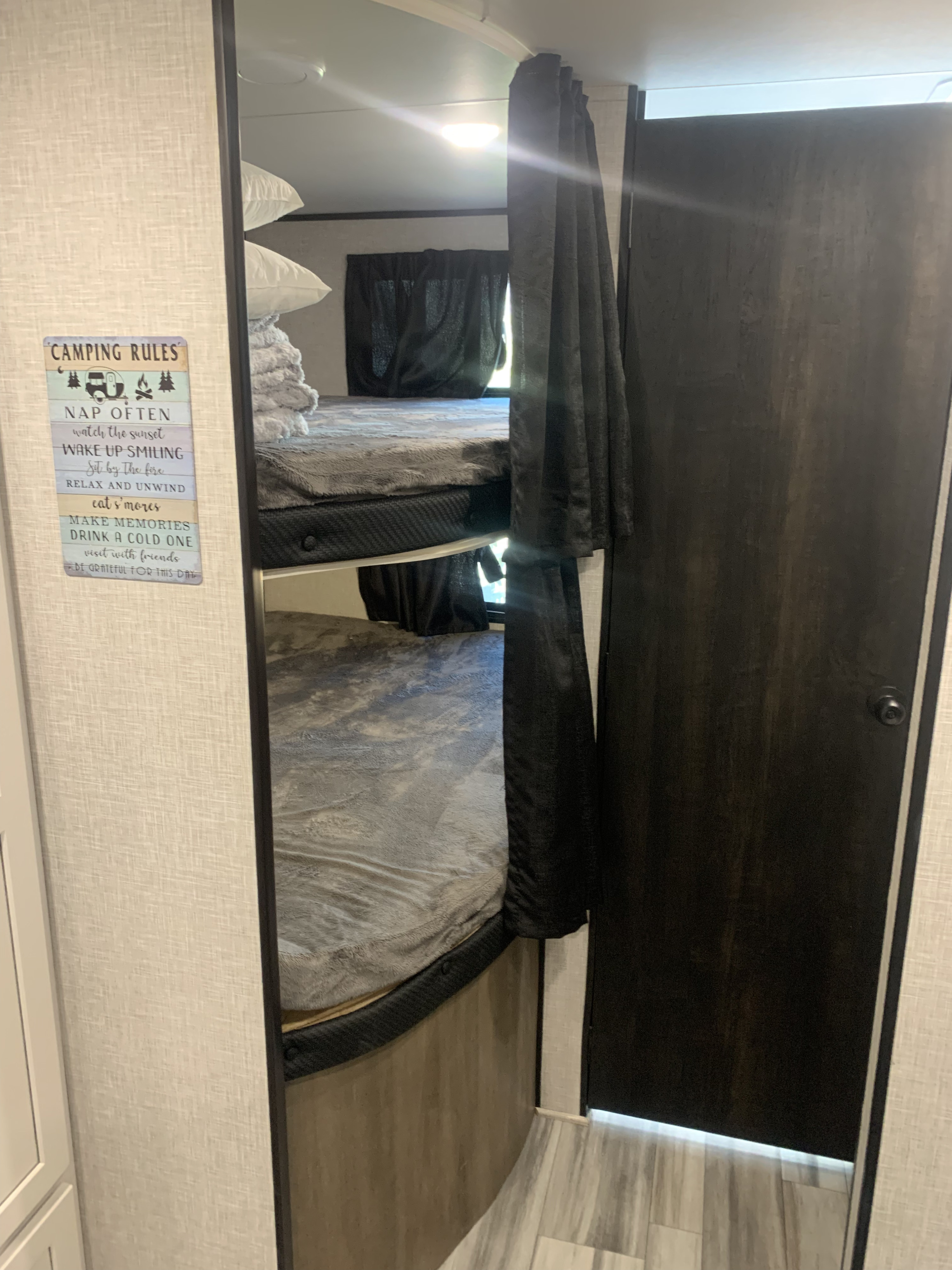 Inside an RV rental: comfy bunk beds with privacy curtains & a fun "Camping Rules" sign. Ideal for camping trips.. Jayco Jay Flight 2024