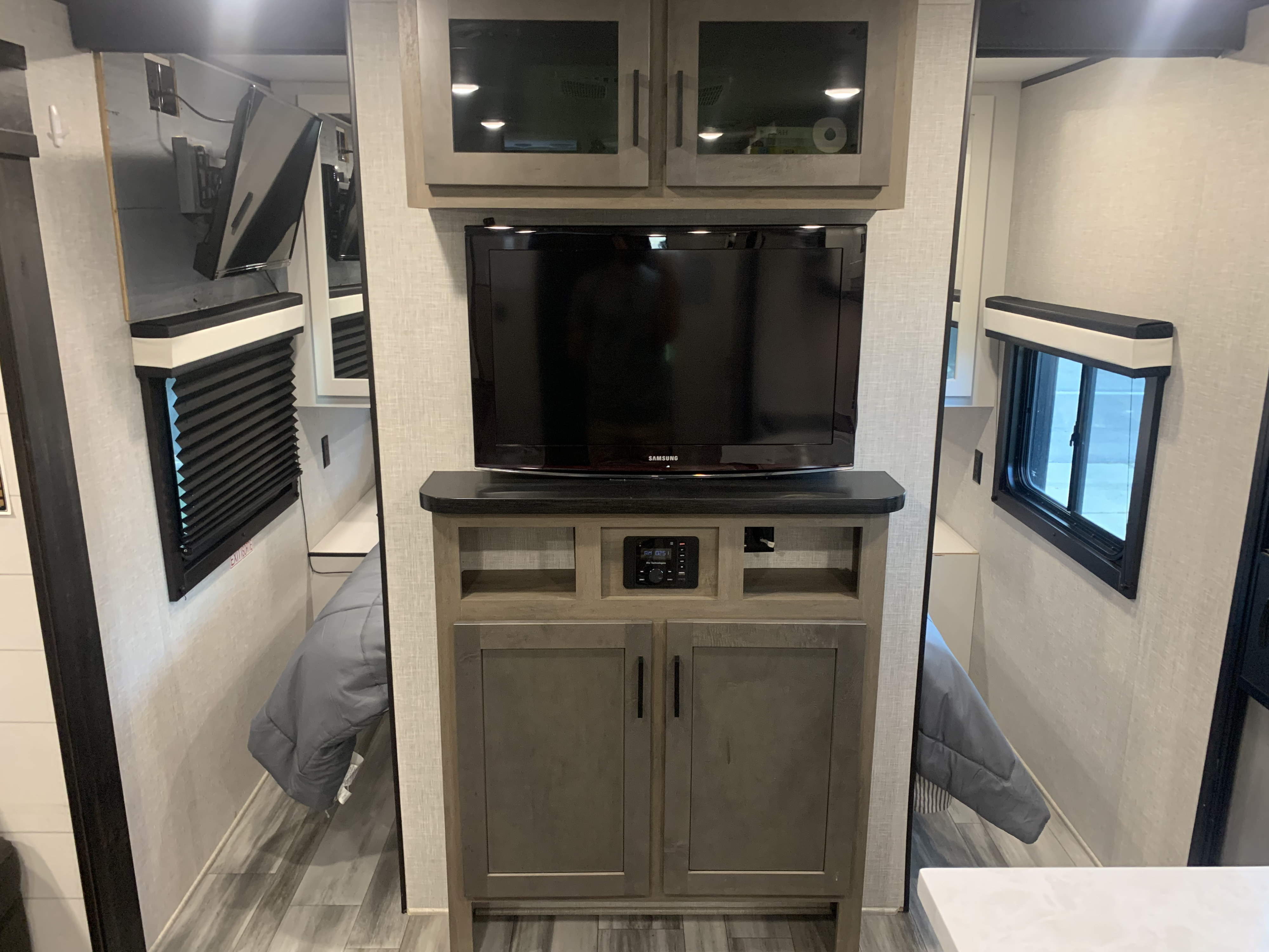 Explore this RV rental: Central entertainment with TV, and comfortable sleeping areas visible on both sides with windows.. Jayco Jay Flight 2024