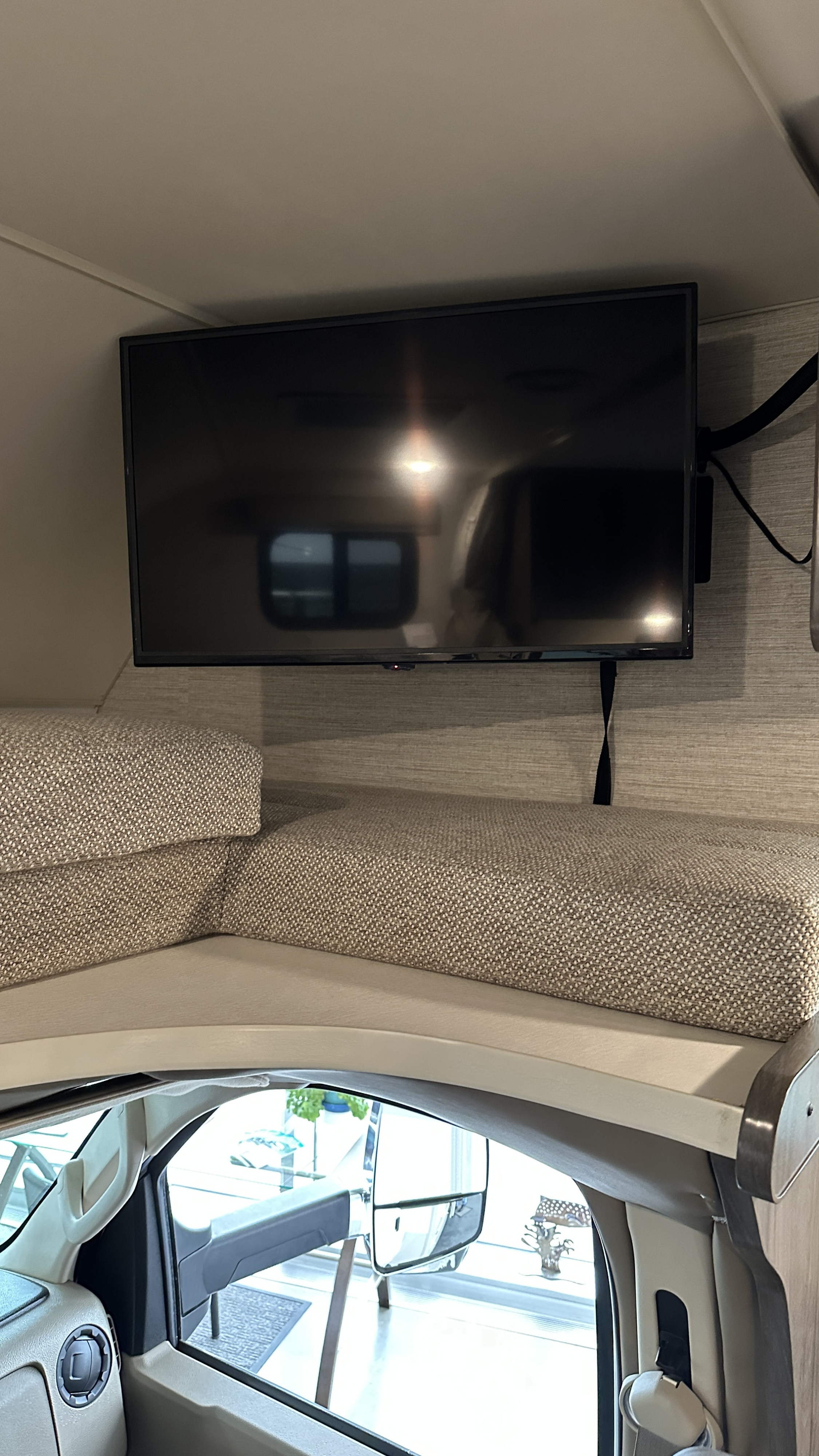 This RV rental features a mounted TV above a cushioned cab-over bunk, providing a cozy sleeping area.. Winnebago Minnie Winnie 2023