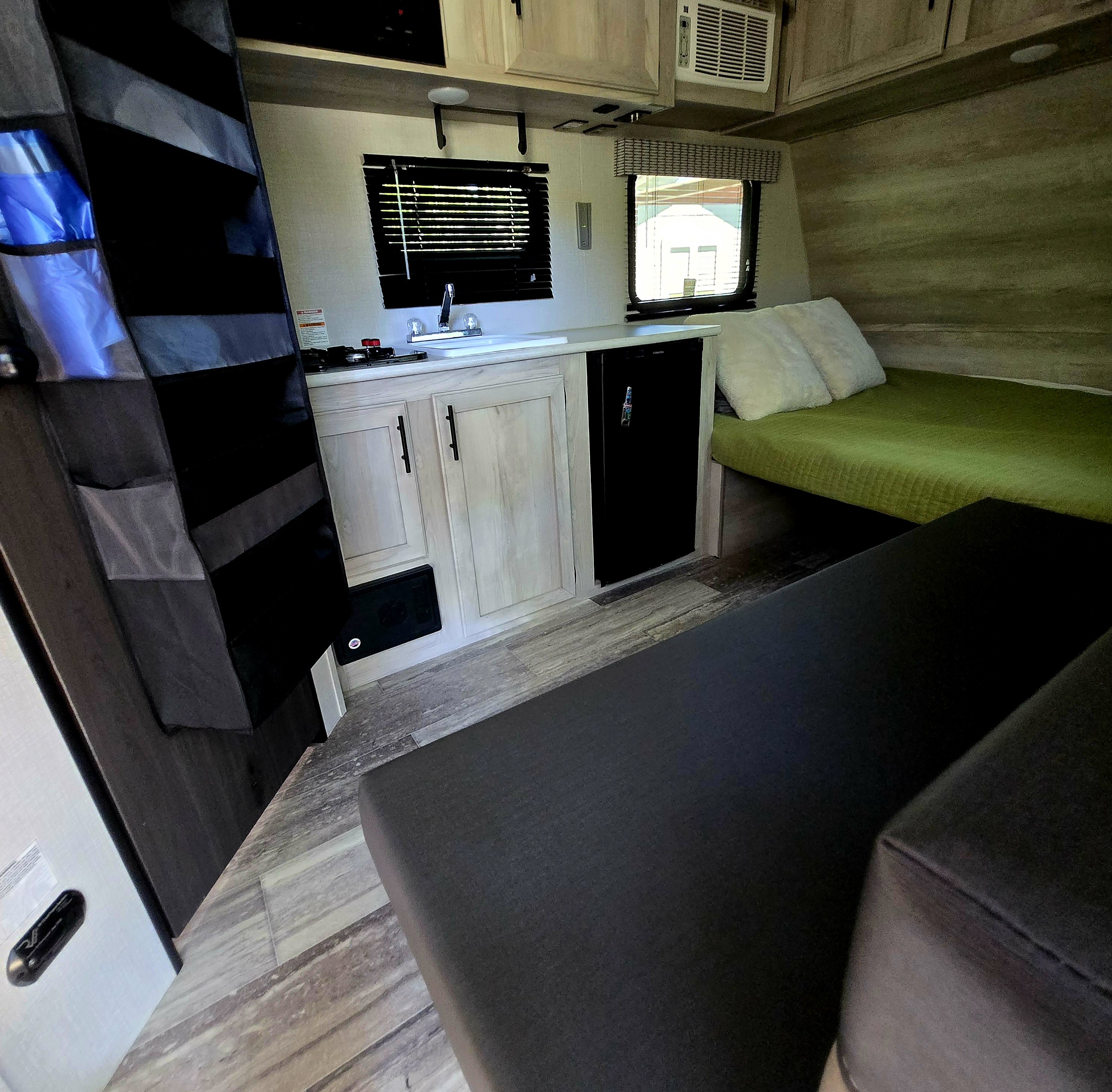 Well-appointed RV rental with a cozy bed, functional kitchenette, and comfy seating, ideal for travel adventures.. KZ 130rb 2021