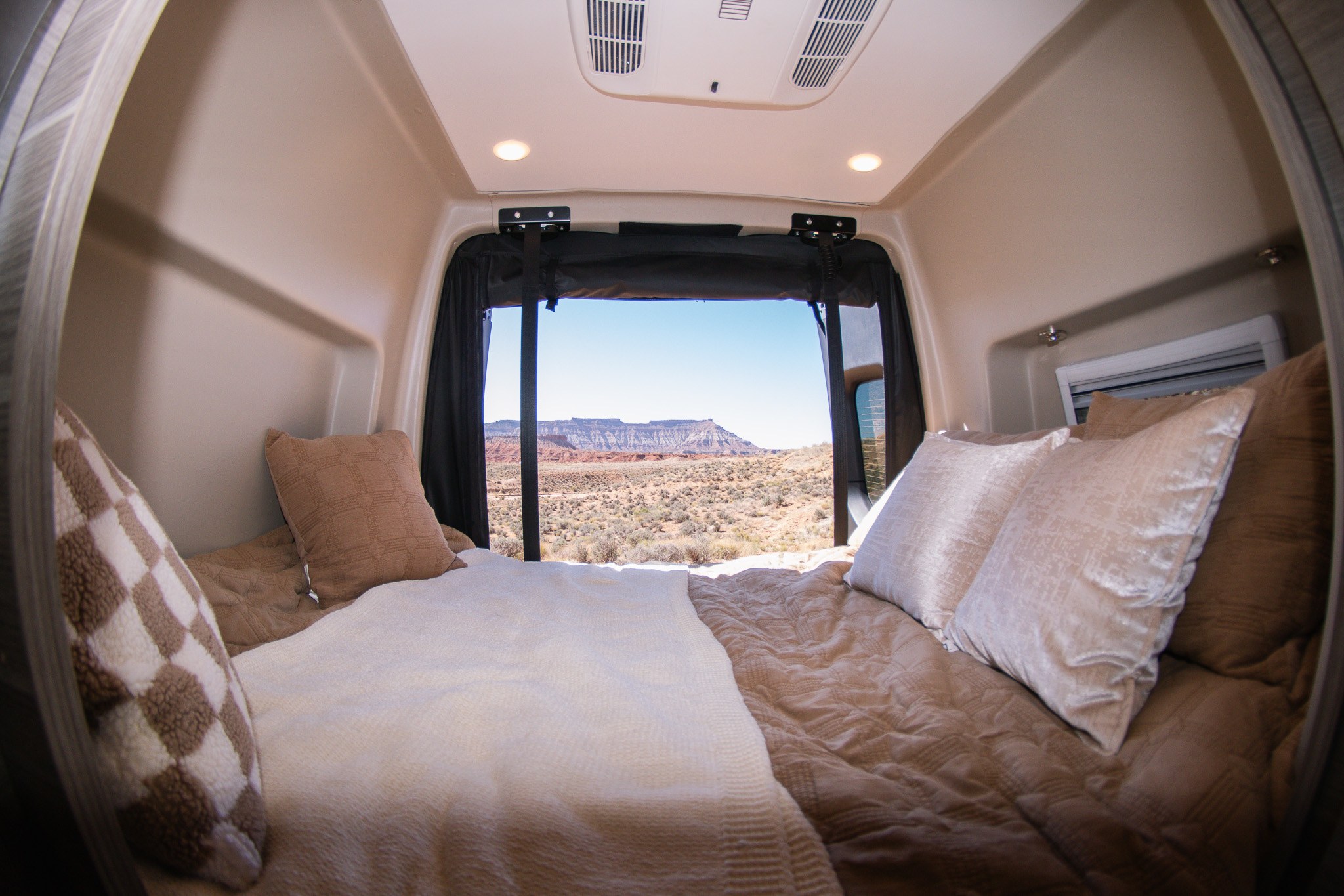 Relax in your RV rental's cozy bed with a stunning desert mountain view. Perfect for scenic travel adventures.. Entegra Coach Launch 2024