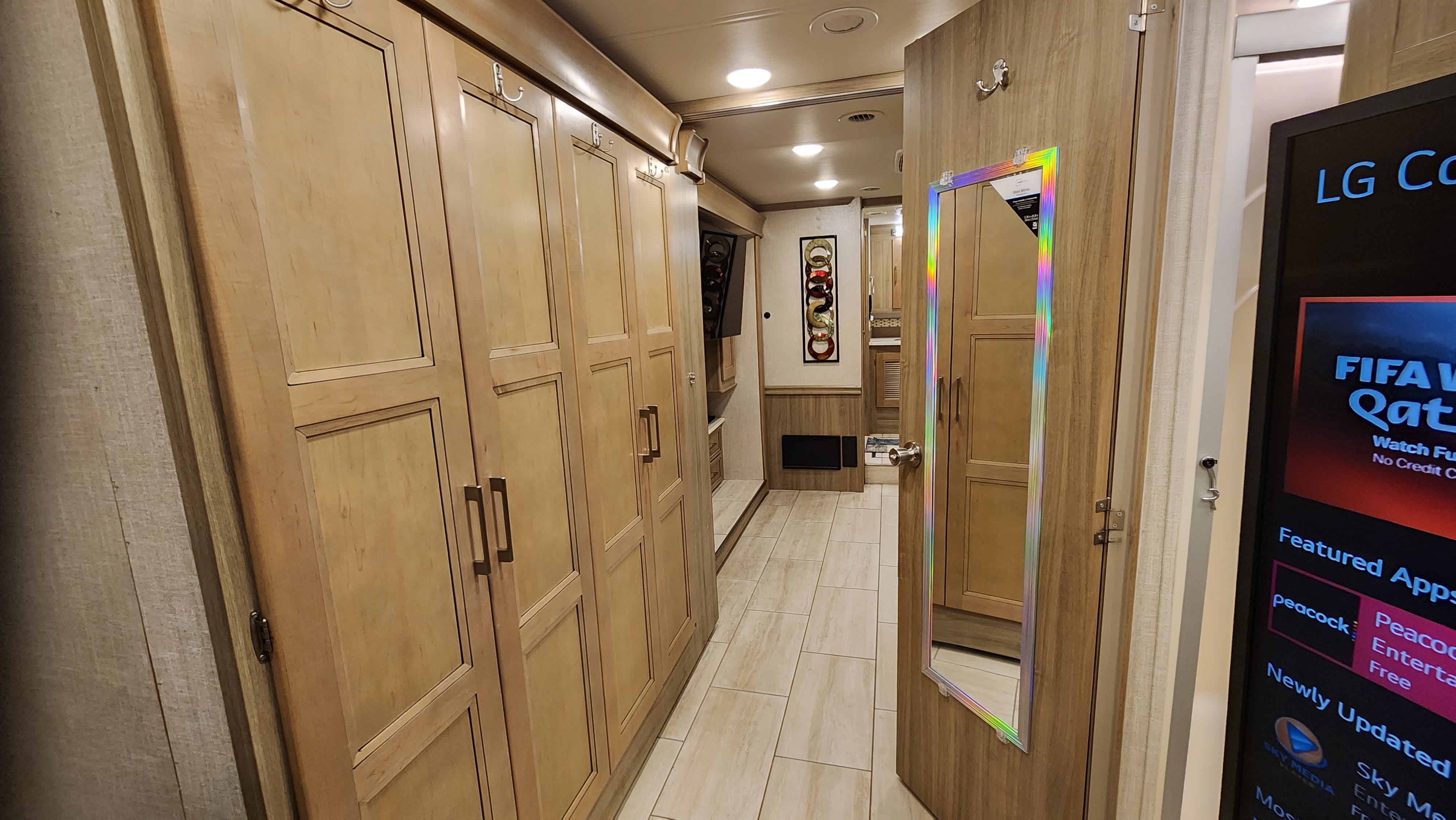 Explore this RV rental's organized interior hallway, featuring extensive light wood cabinets, tiled flooring, and a mirrored door.. Forest River Coachmen Sportscoach 2019