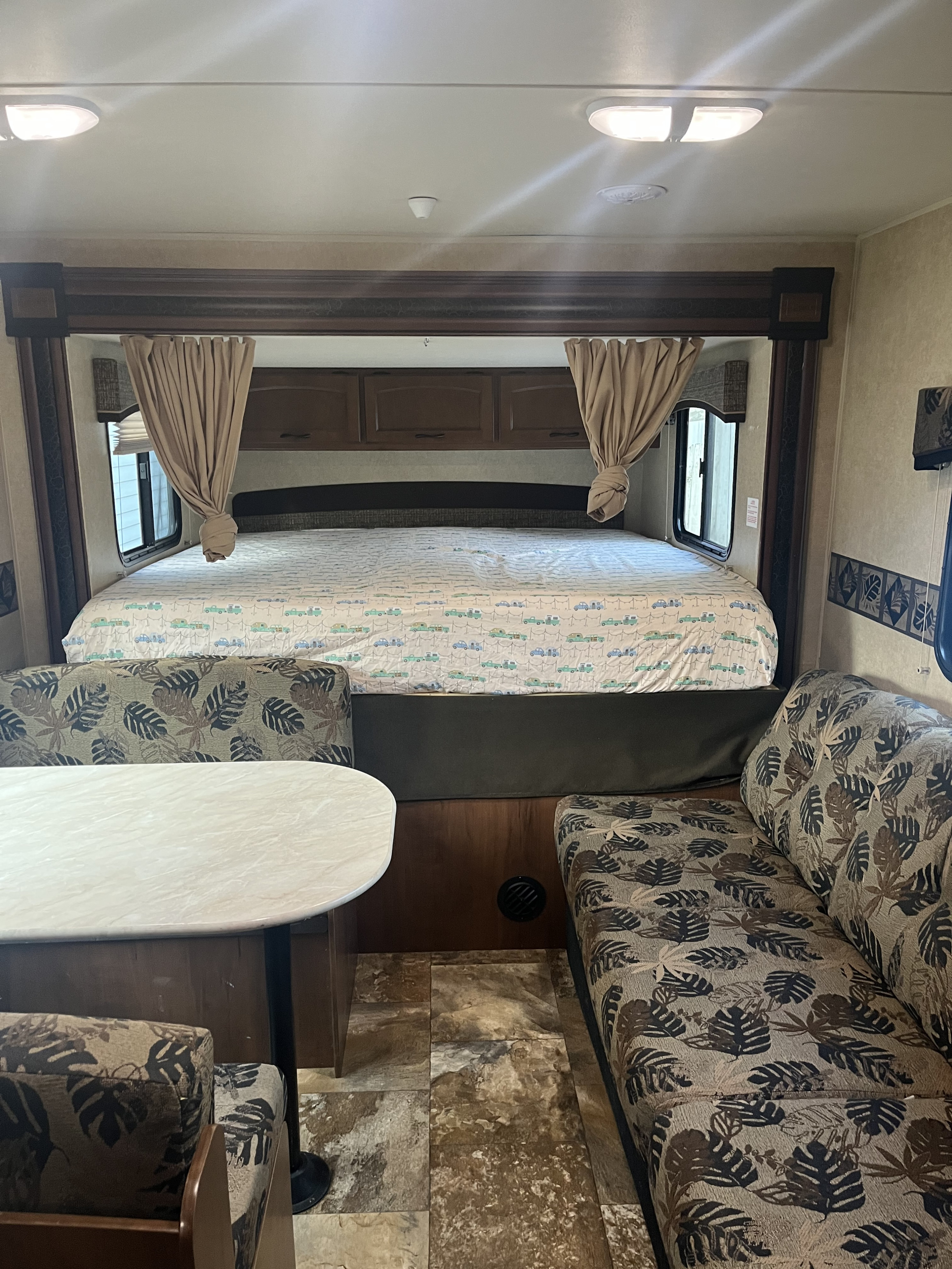 Spacious RV rental interior featuring a cozy bed with fun vehicle sheets & a dinette with leafy cushions. Ready for adventure!. Jayco Jay Feather Ultra Lite 2014