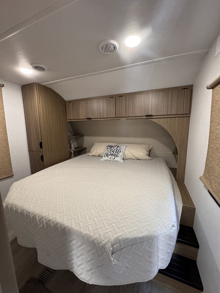 RV rental bedroom interior: a comfortable bed with quilted cover, overhead storage, and wardrobe.. Forest River Salem 31kqbts 2025