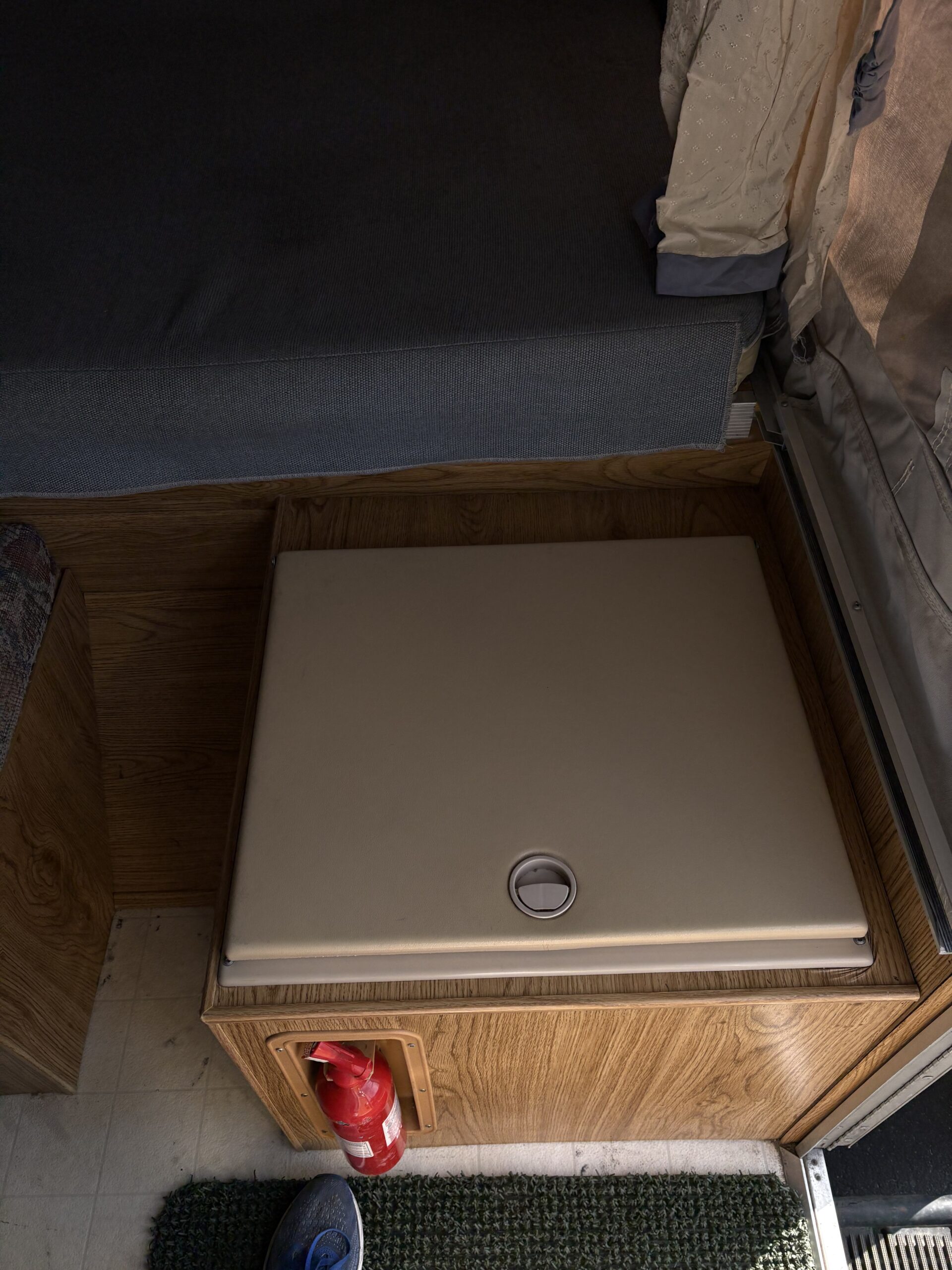 Inside an RV rental: a compact bed/seating area, a functional table, and a fire extinguisher for safety.. Forest River Palomino Colt 1994