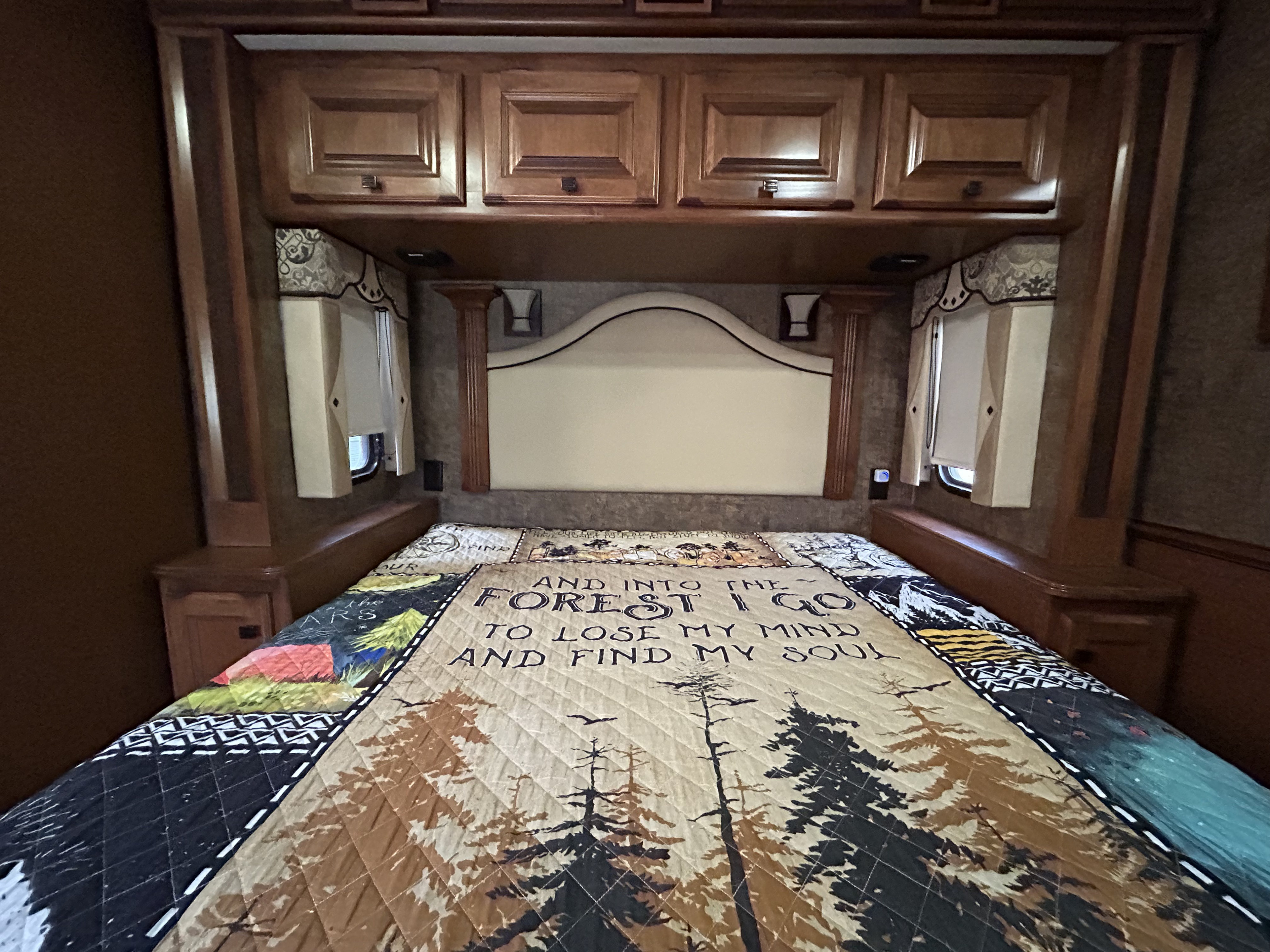 Cozy RV rental bedroom with a nature-themed quilt and ample storage cabinets, ready for your next adventure.. Tiffin 34 TGA 2012