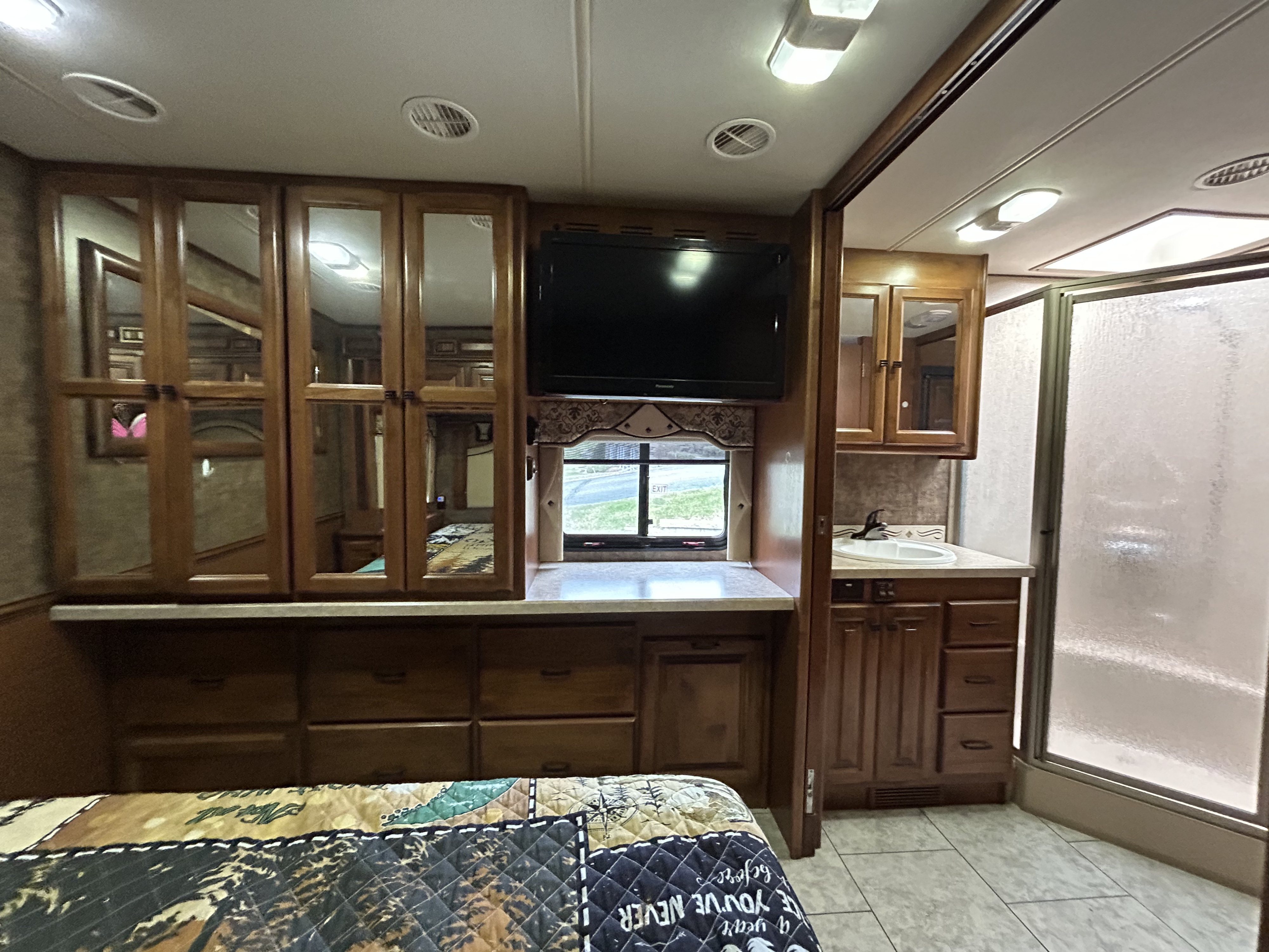 Spacious RV rental interior with bedroom, mirrored cabinets, TV, and en-suite bathroom with shower and sink.. Tiffin 34 TGA 2012