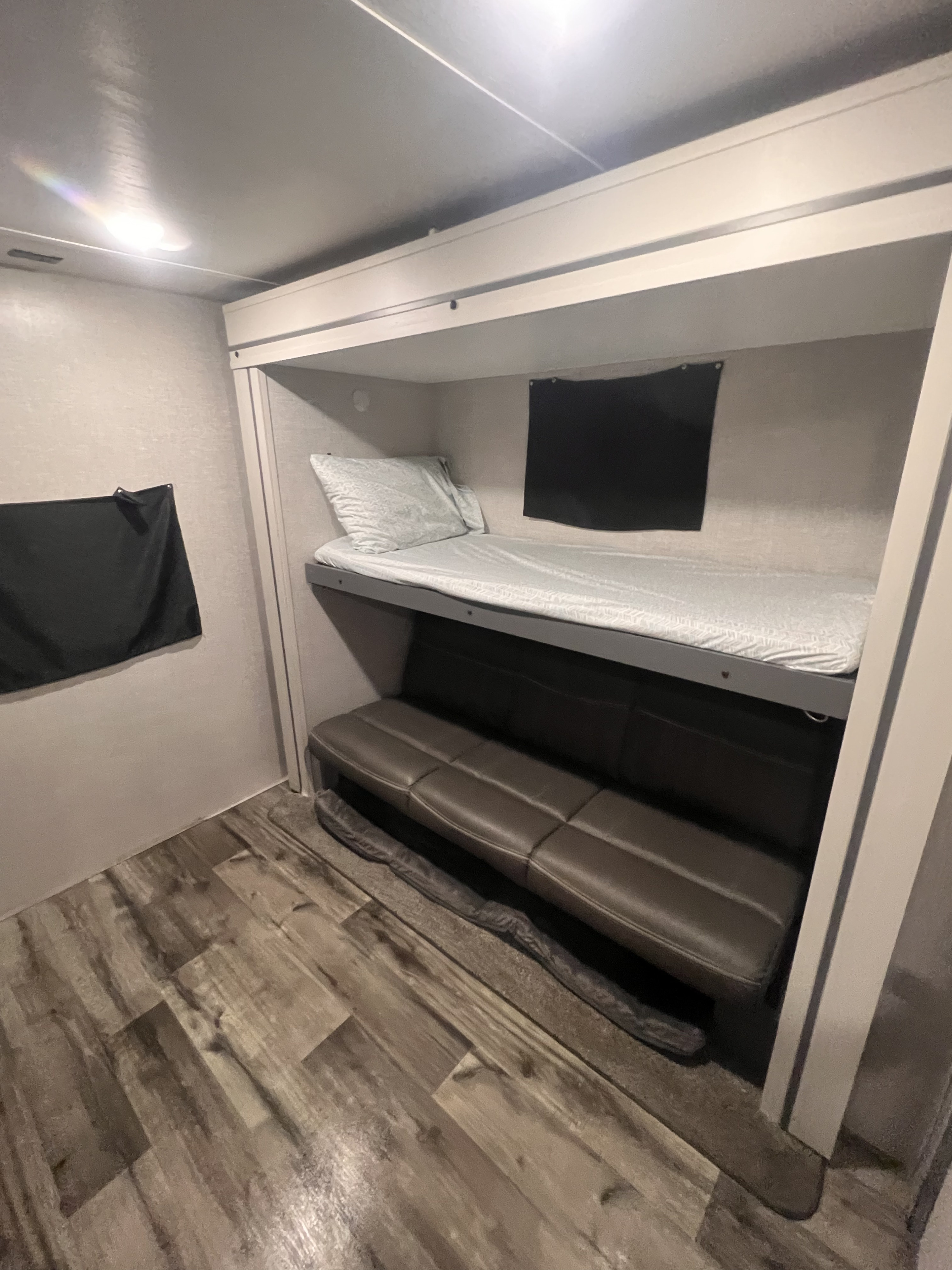 Cozy RV rental interior with bunk beds, a pull-out sofa, and wood-look flooring. Perfect compact sleeping space.. Crossroads Volante 2022