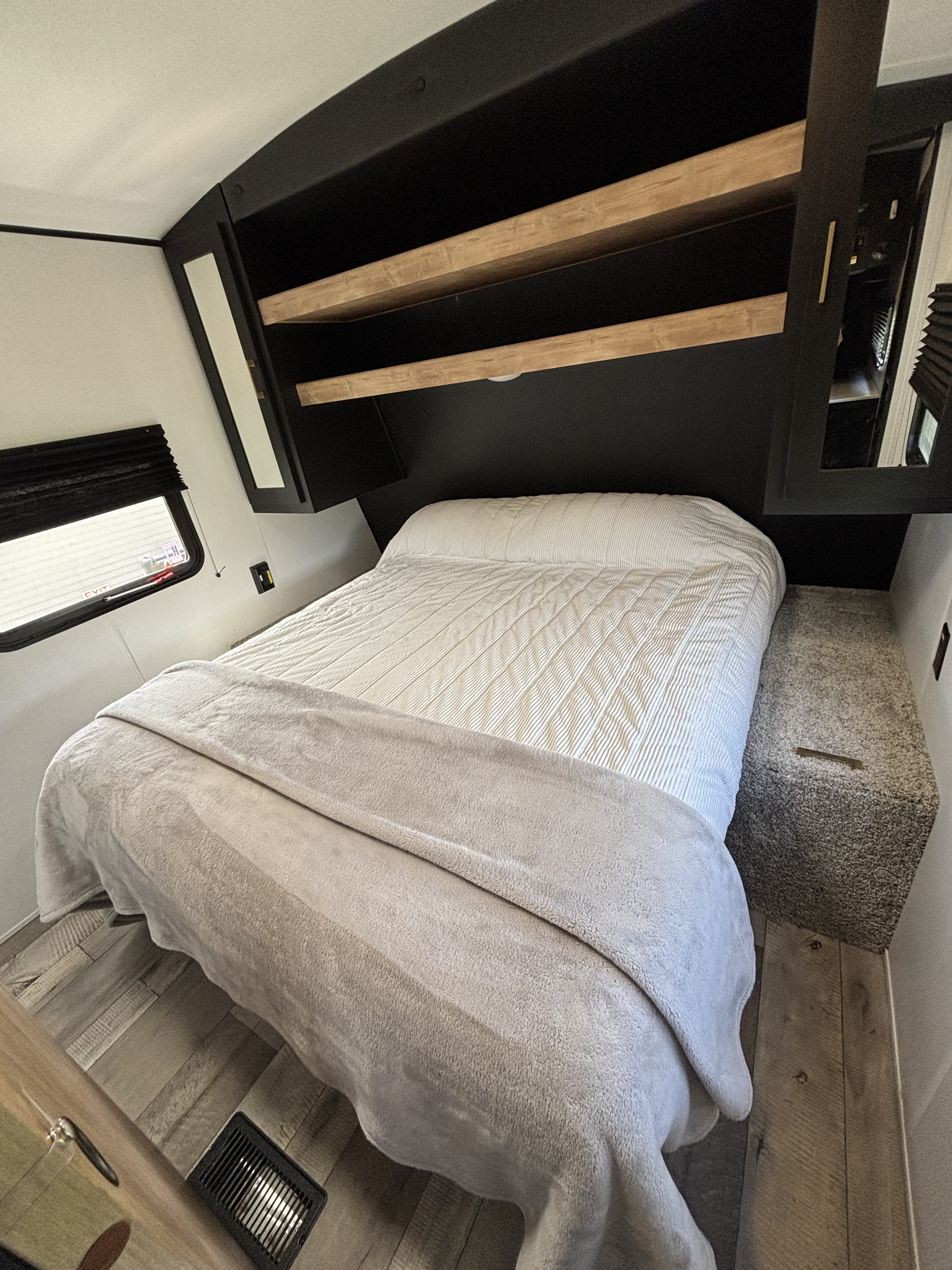 Cozy RV rental bedroom with a comfortable bed, overhead wooden shelves, and mirrored cabinet.. Keystone Spring Dale 2022