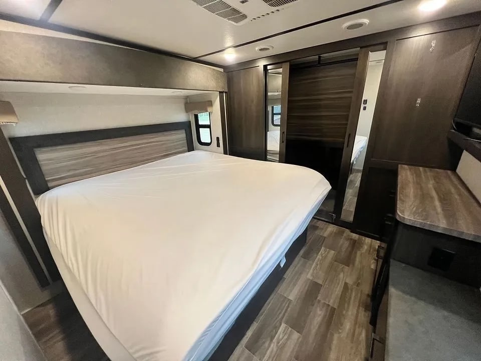 RV rental bedroom: a comfortable bed with wood headboard, mirrored sliding doors, and ample storage for travel.. Crossroads RV Cruiser 2020