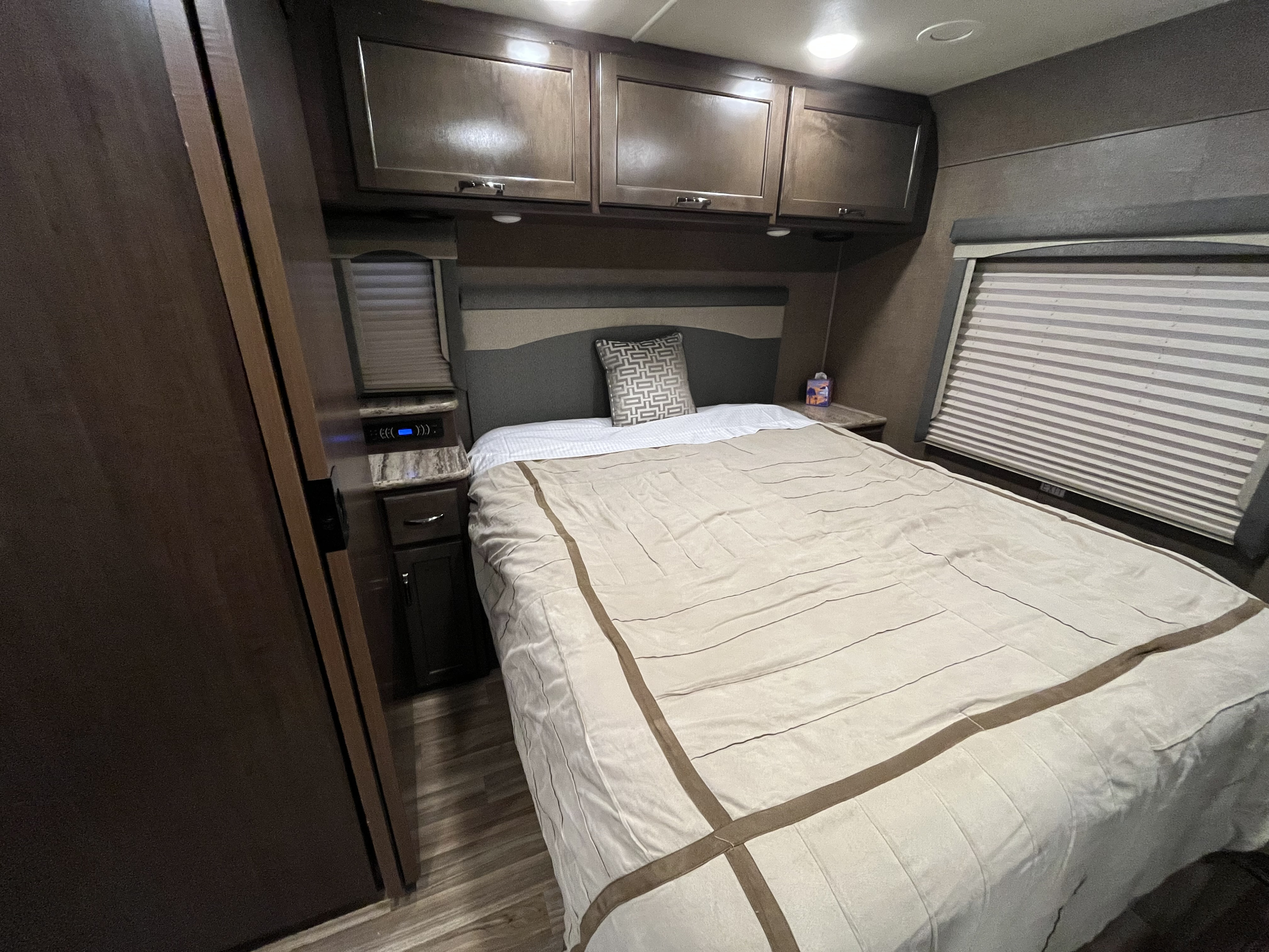 Inviting rv rental bedroom with a comfortable bed, overhead cabinets, and window blinds.. Thor A.C.E. 2016
