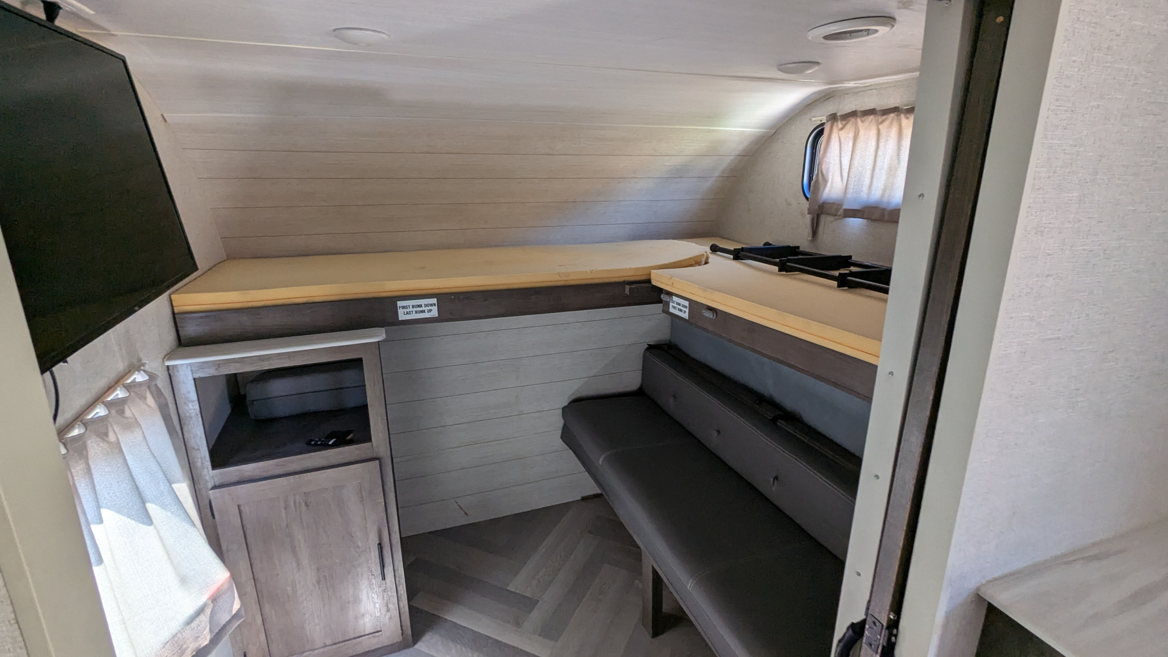 This RV rental interior features convertible bunk beds, a lower bench, and a mounted TV, maximizing space for travelers.. Forest River Salem 2021