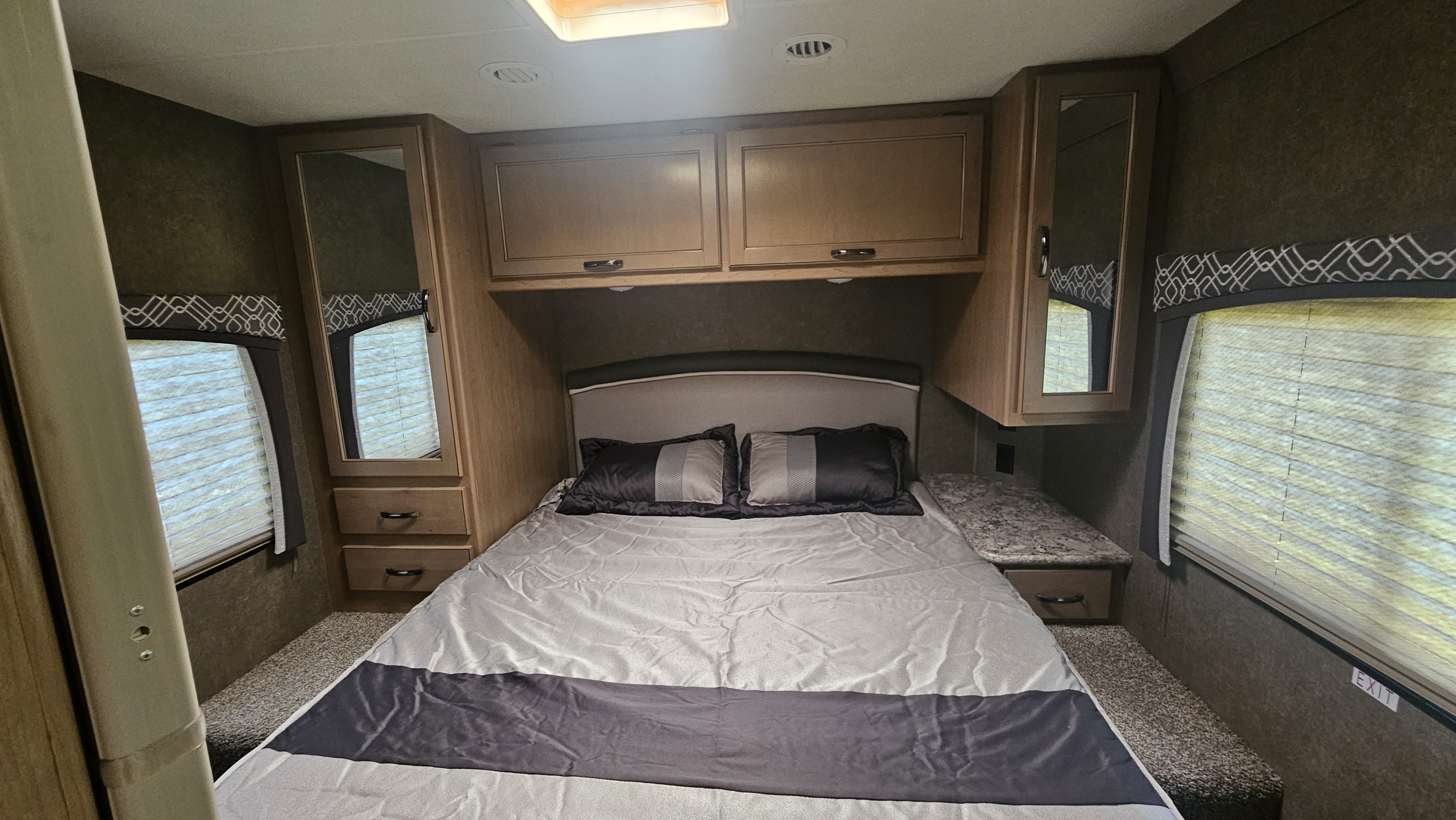RV rental bedroom with bed, overhead cabinets, side storage, and windows, designed for comfort.. Thor Chateau 2020