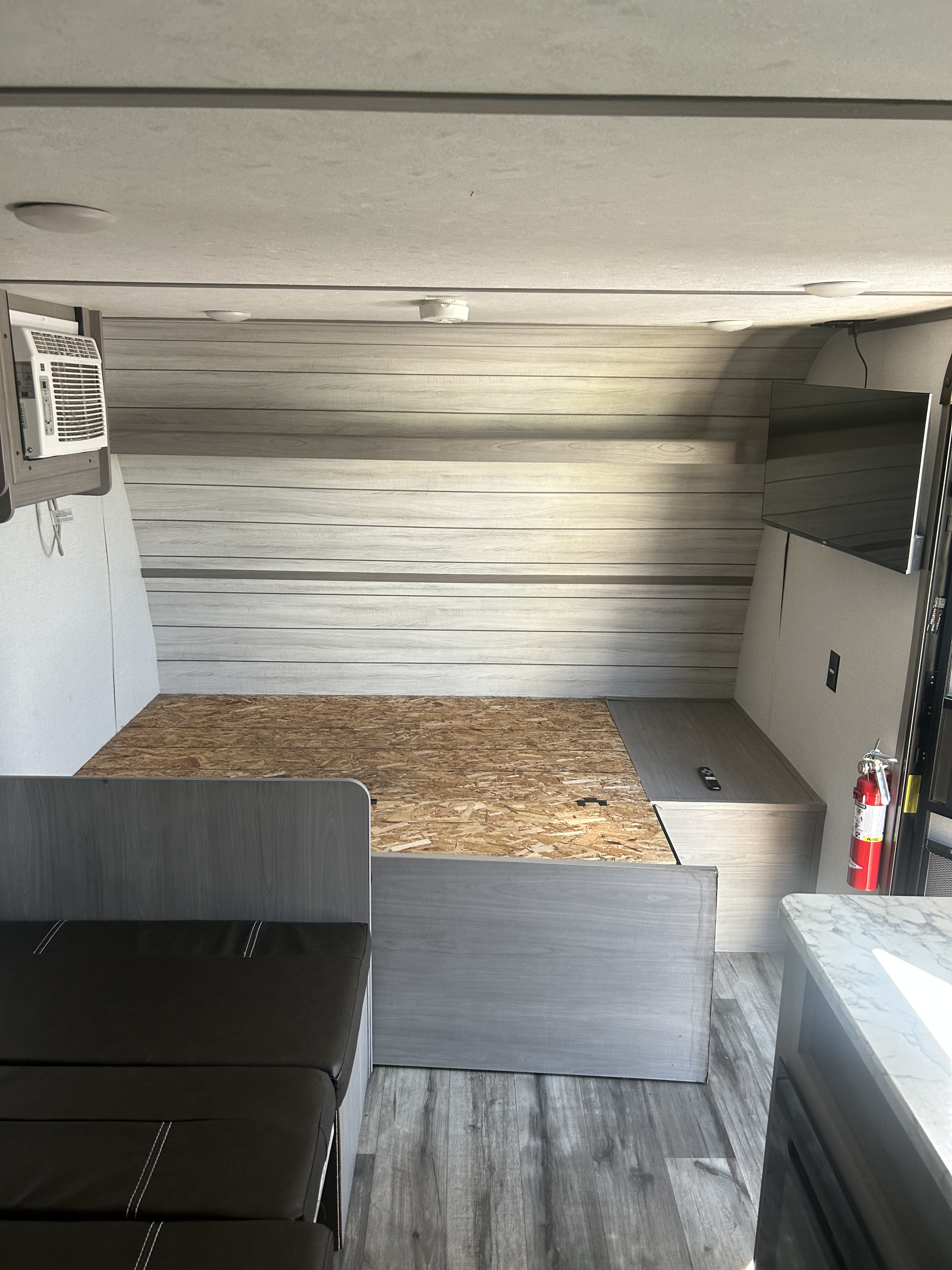 RV rental interior: Bed platform, lounge seating, AC, TV, and a fire extinguisher for safety and comfort.. Dutchmen Coleman 17B 2022