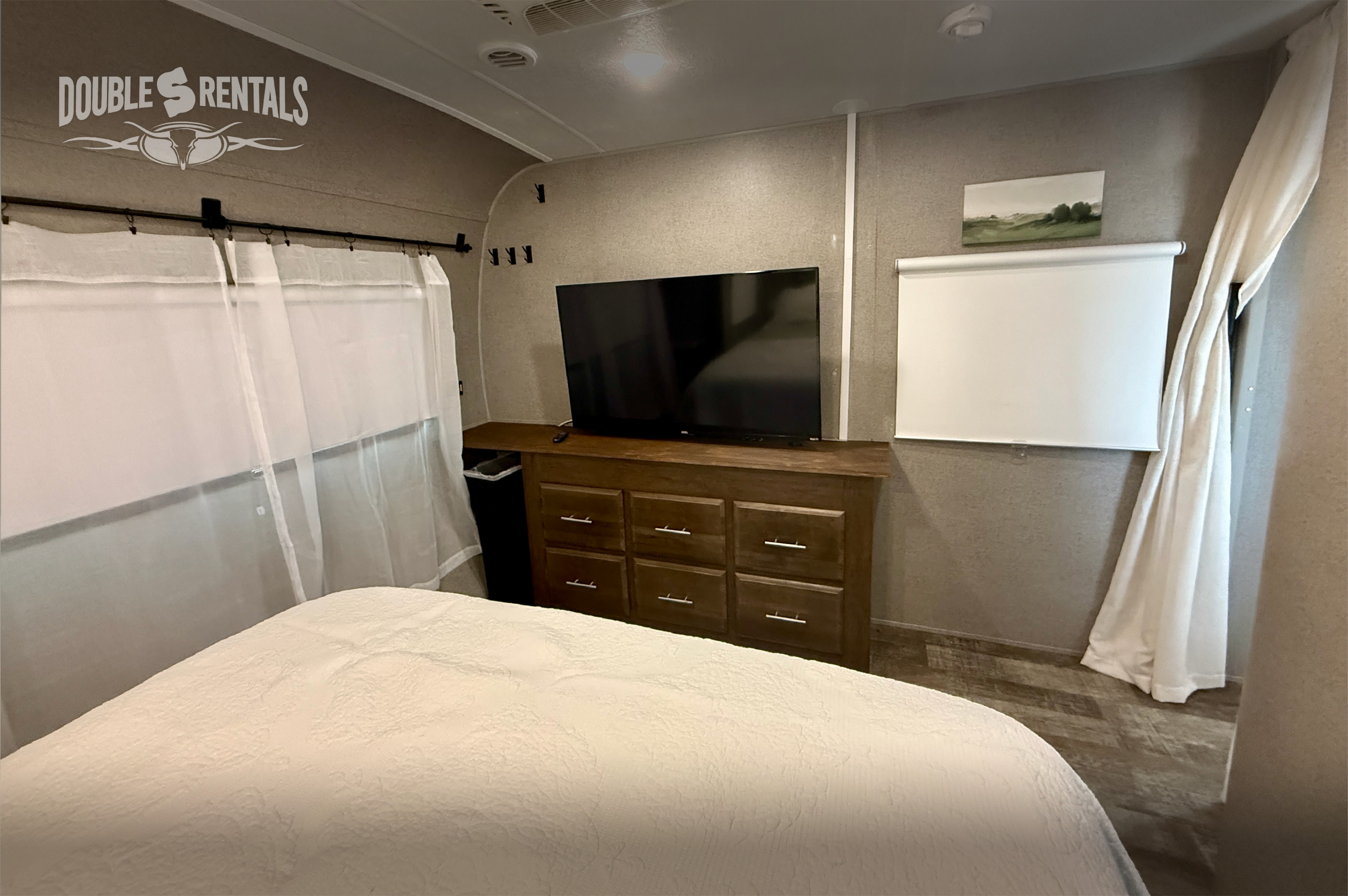 Spacious RV rental bedroom with TV, dresser, and comfortable bedding, ideal for relaxing trips.. Forest River Rockwood Signature 2019
