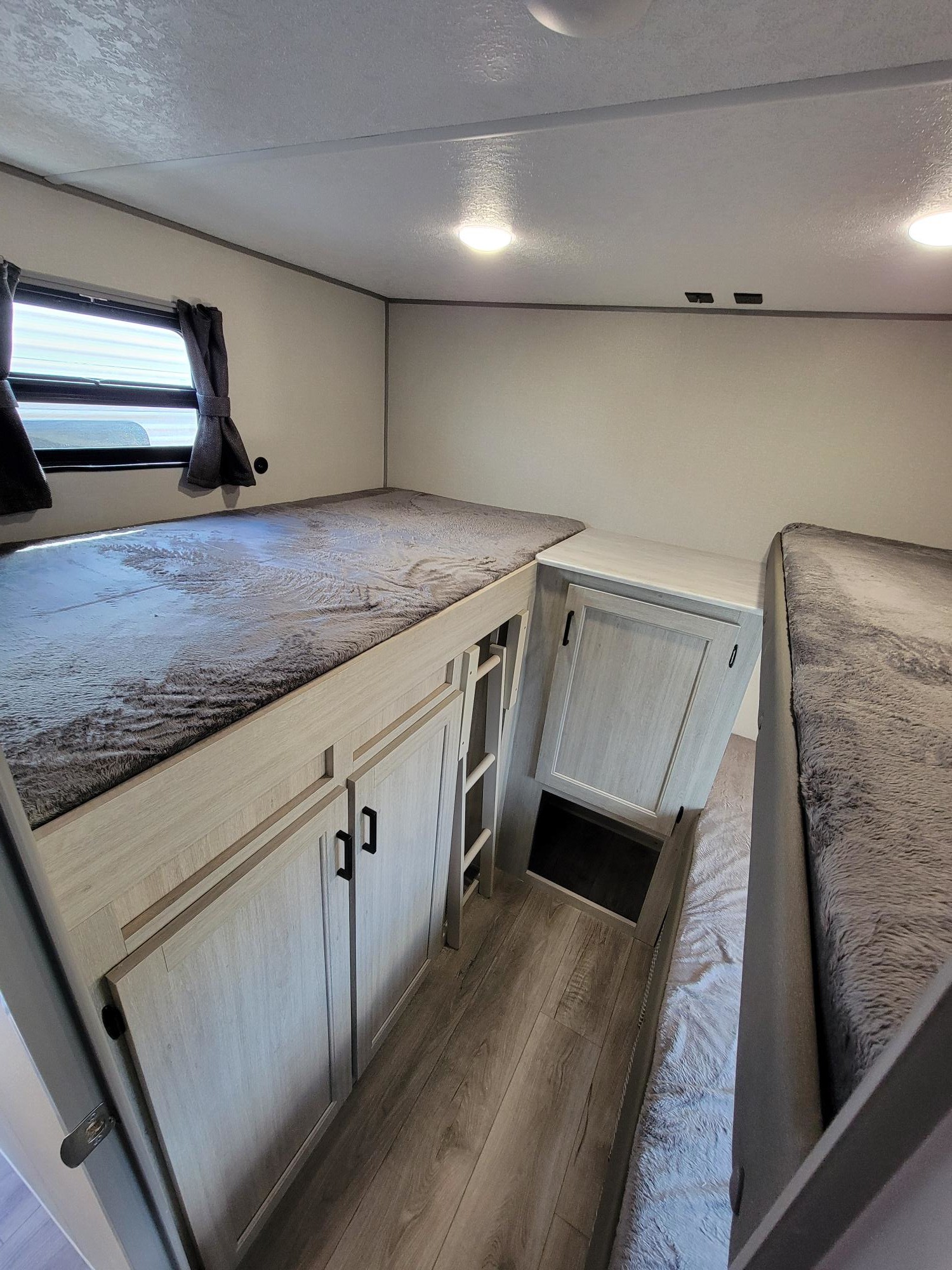 Inside this RV rental, find multiple bunk beds with soft grey bedding, light wood cabinetry, and a window. Perfect for group sleeping.. Coachmen Catalina 2025