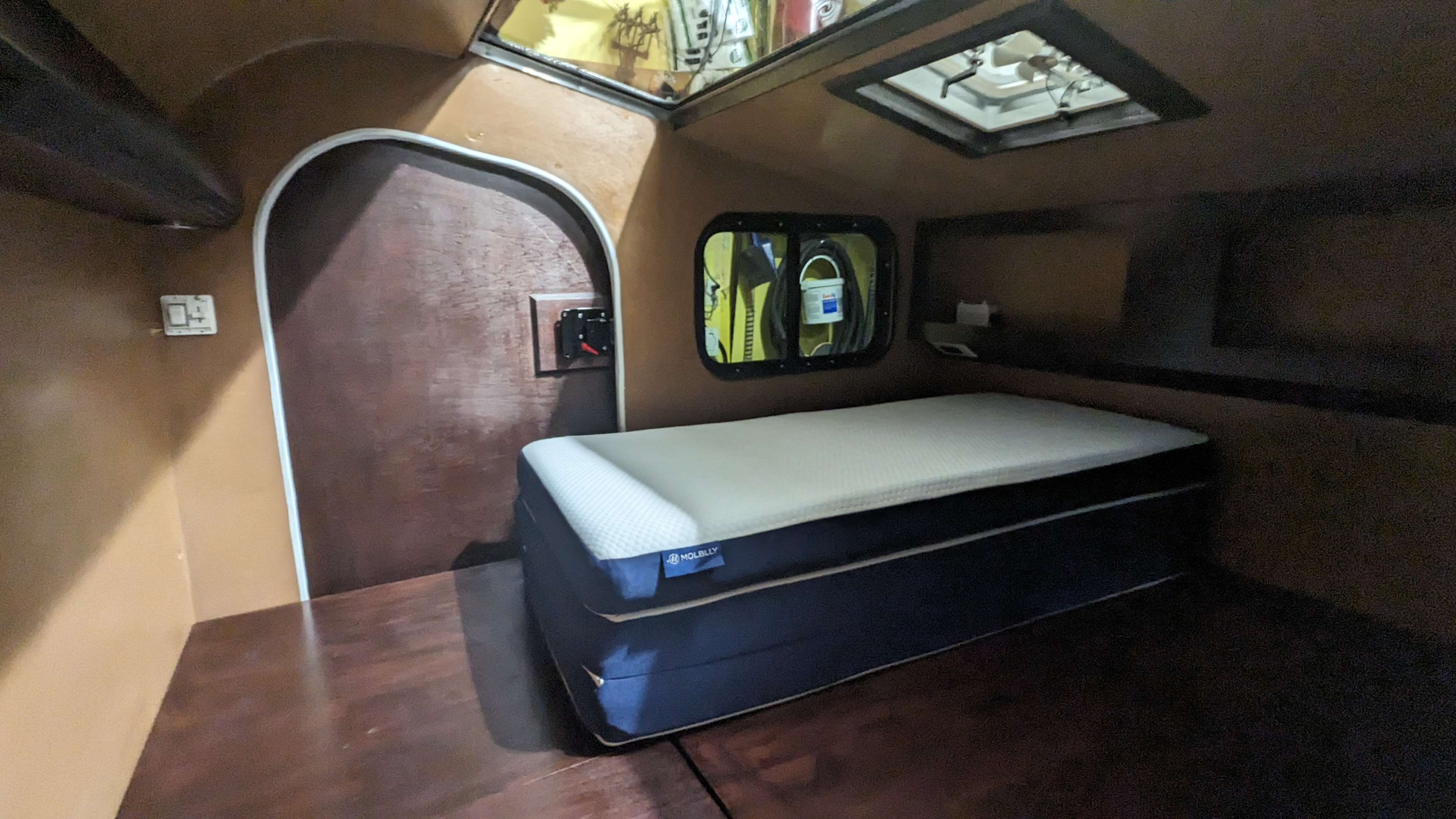Cozy RV rental cabin interior featuring a comfortable bed, compact design, and overhead ventilation.. Custom Blu Paw 2024