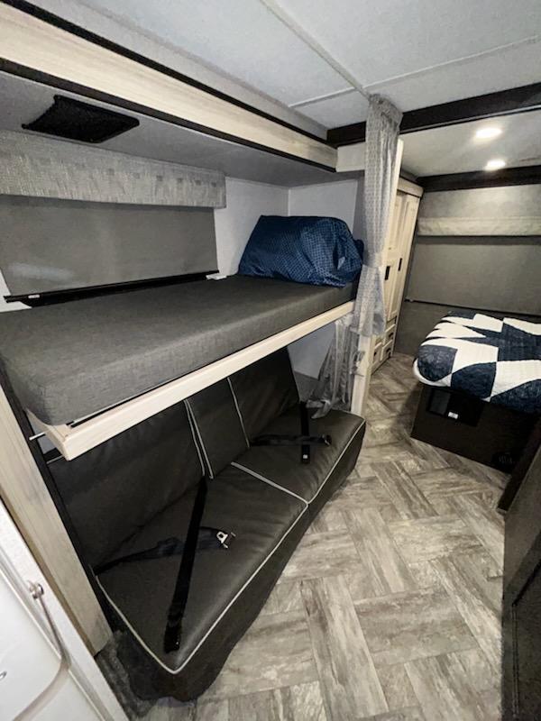 Inside this RV rental: a bunk bed with a lower sofa-sleeper and patterned flooring. Perfect for family adventures.. Forest River Sunseeker 2022