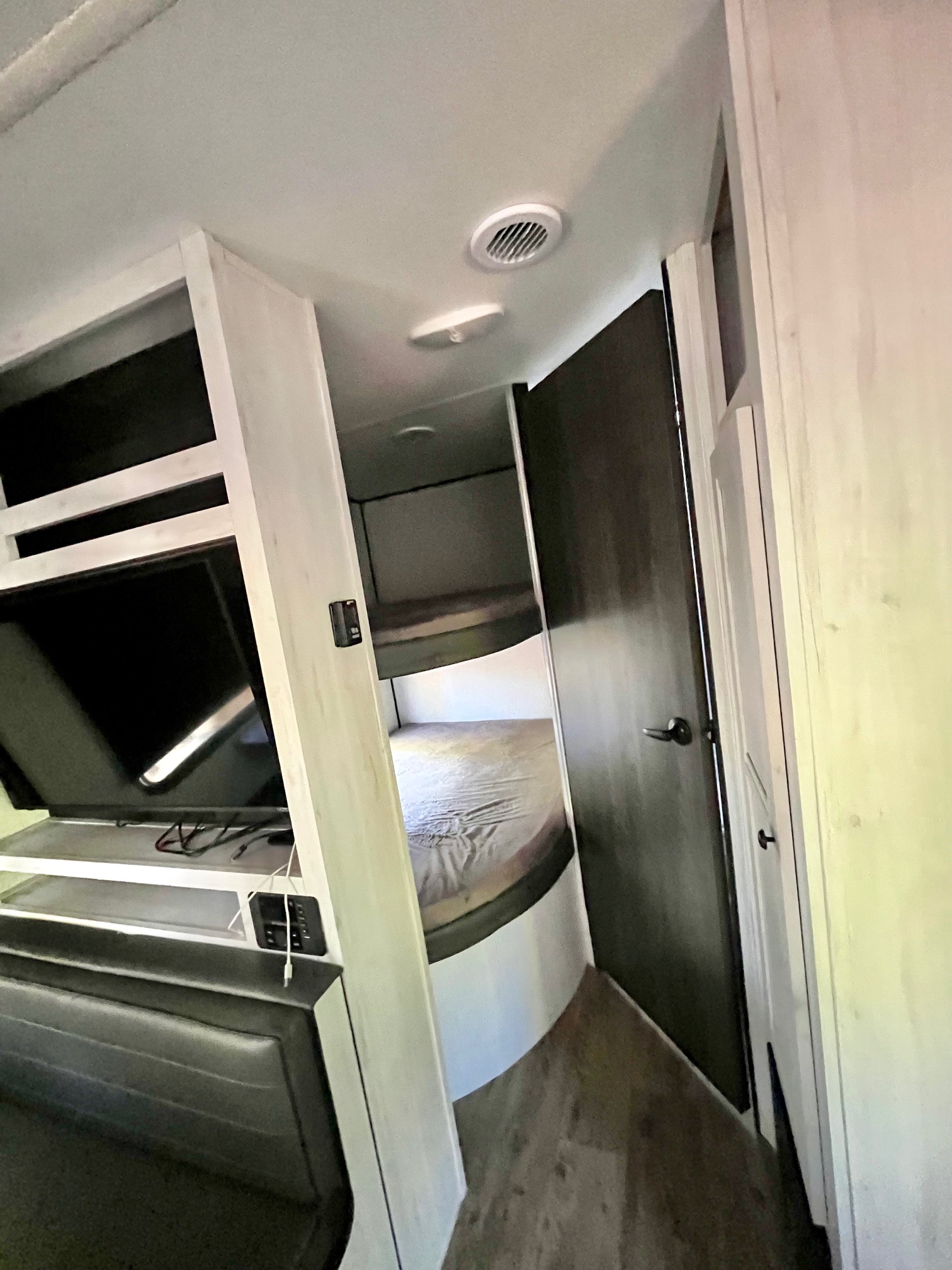 Experience RV rental comfort: View inside a compact RV showing bunk beds, a mounted TV, and seating in a bright interior.. Heartland RVs Trail Runner 2023