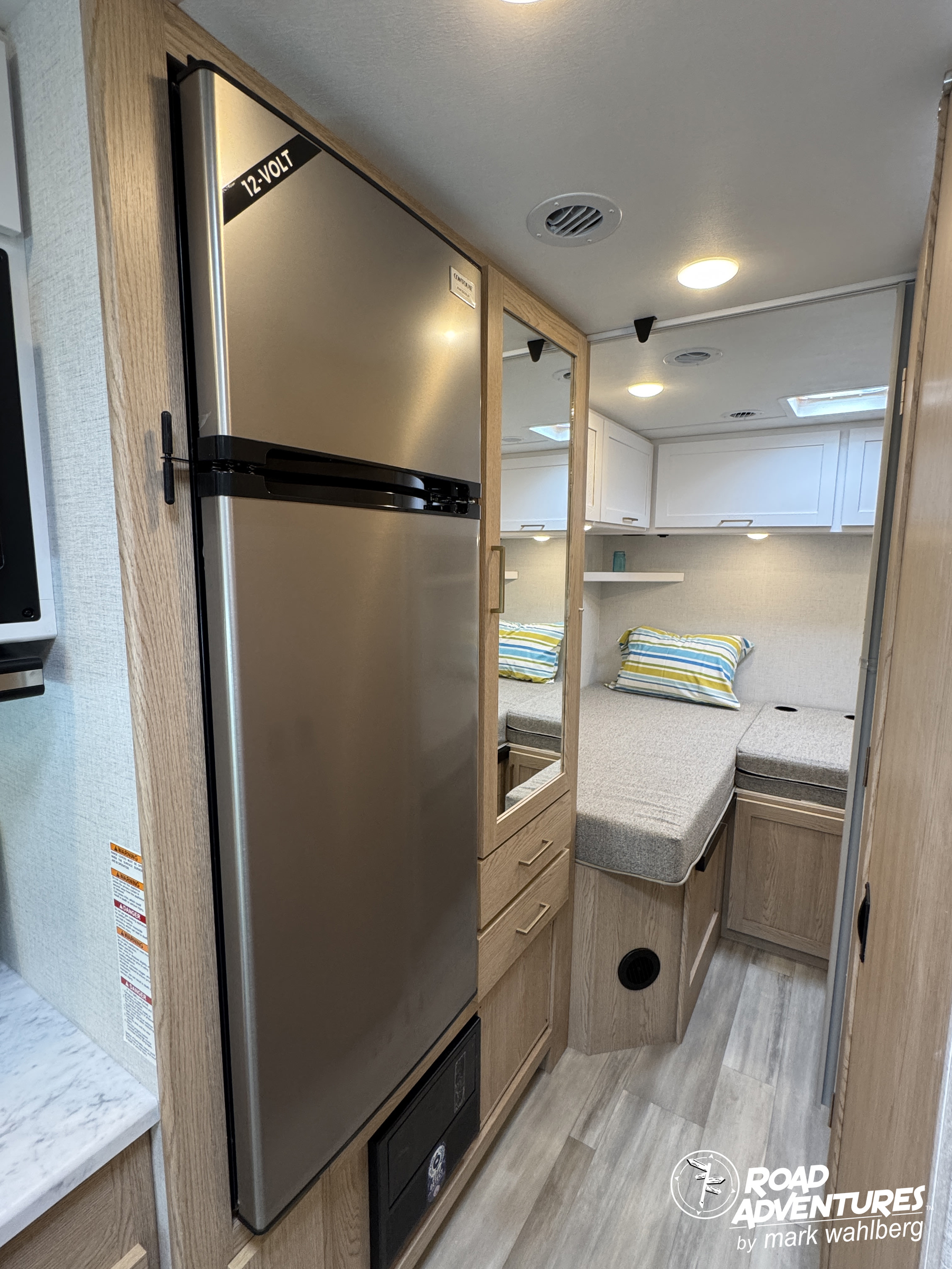 Explore your rv rental! This view features a 12-volt fridge, mirrored storage, and a comfy dinette area.. Thor Motor Coach Four Winds 2026
