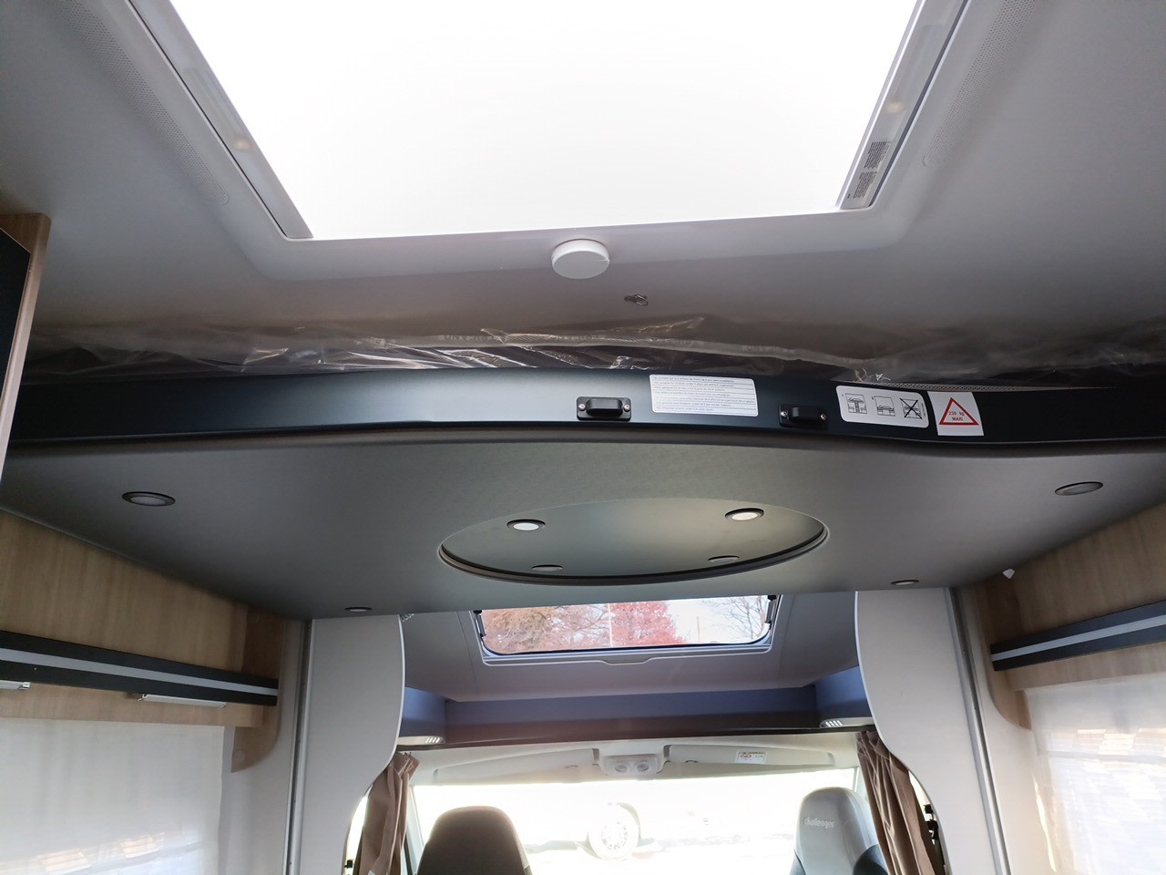 Looking up in an RV rental: spacious interior with a stowed drop-down bed (200kg max), large skylight, and ceiling lights.. Challenger 384 Family 2024