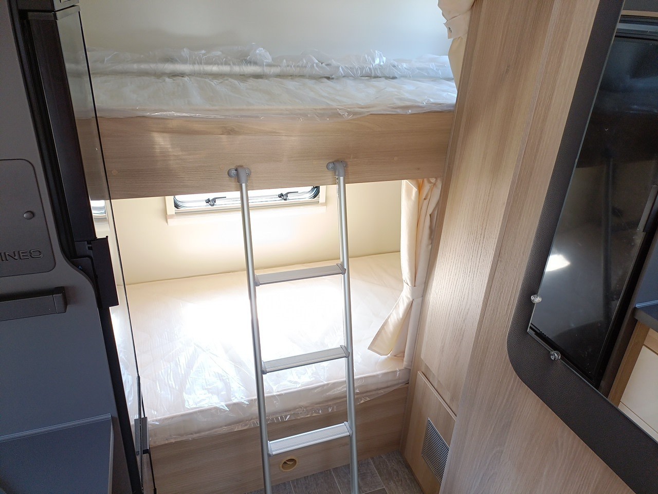 Compact RV rental interior features bunk beds, ladder, and new wrapped mattresses, ready for travel.. Itinéo PS 700 2024