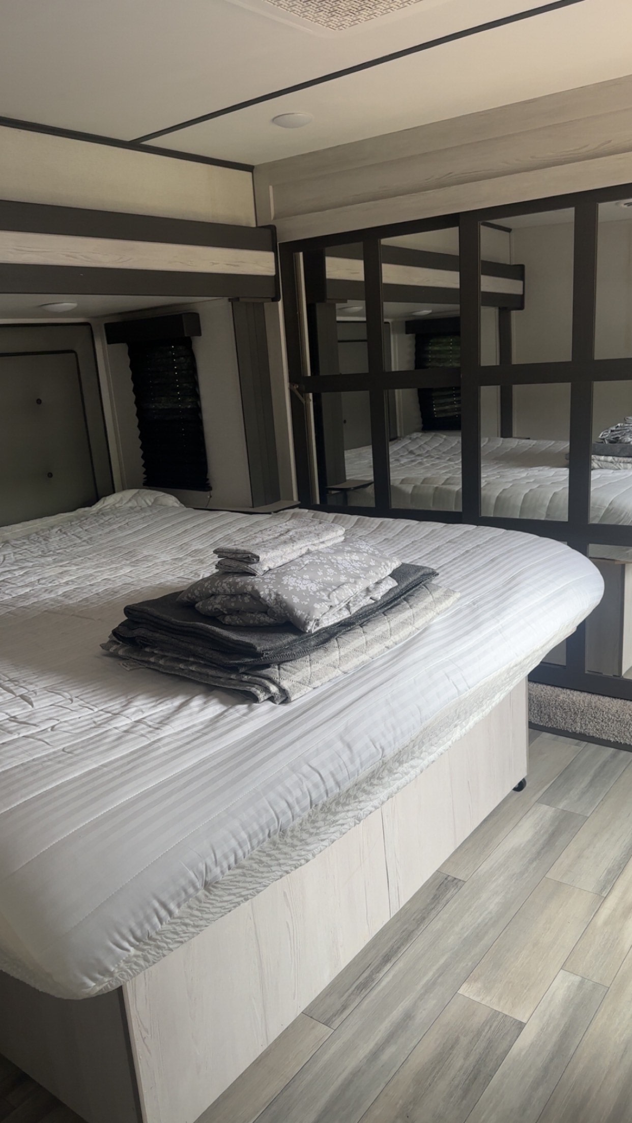 Modern RV rental bedroom featuring a spacious bed with fresh linens and mirrored closet, offering comfort for travel.. Keystone Sprinter 2022
