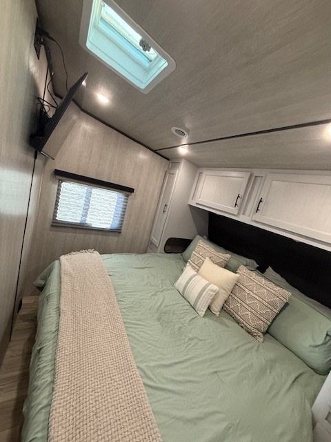 Cozy rv rental bedroom features a comfy bed, mounted TV, overhead cabinets, and a skylight for your travels.. Genesis Supreme Rv Genesis Supreme 2025