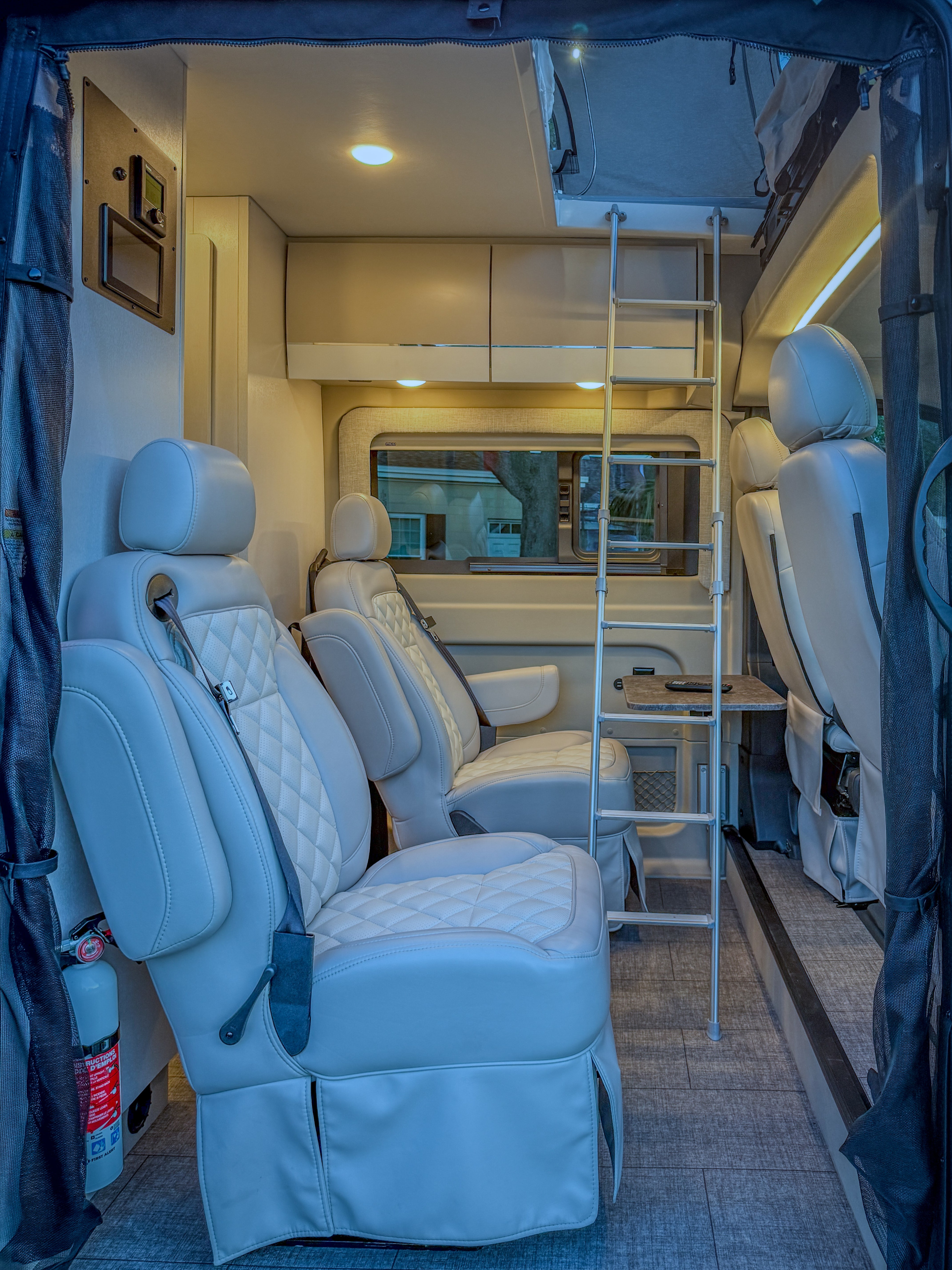 An RV rental showing its light-toned, spacious interior with two captain's chairs, an overhead bunk ladder, and storage.. ENTEGRA ETHOS 2025