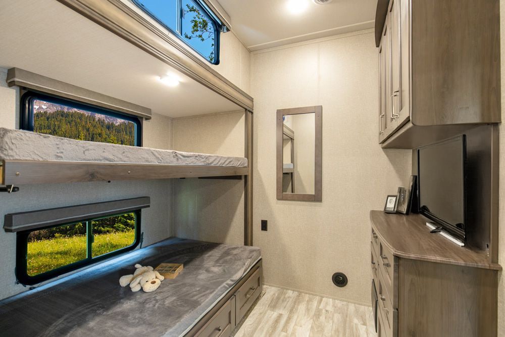 Spacious RV rental interior featuring cozy bunk beds with scenic windows, TV, and storage for comfortable travel.. Grand Design Reflection 2021