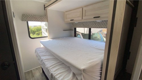 RV rental interior: A compact sleeping area with two bunk beds. White sheets, light wood cabinets, and window views. Ideal for families.. SunSeeker 2250SLE 2024