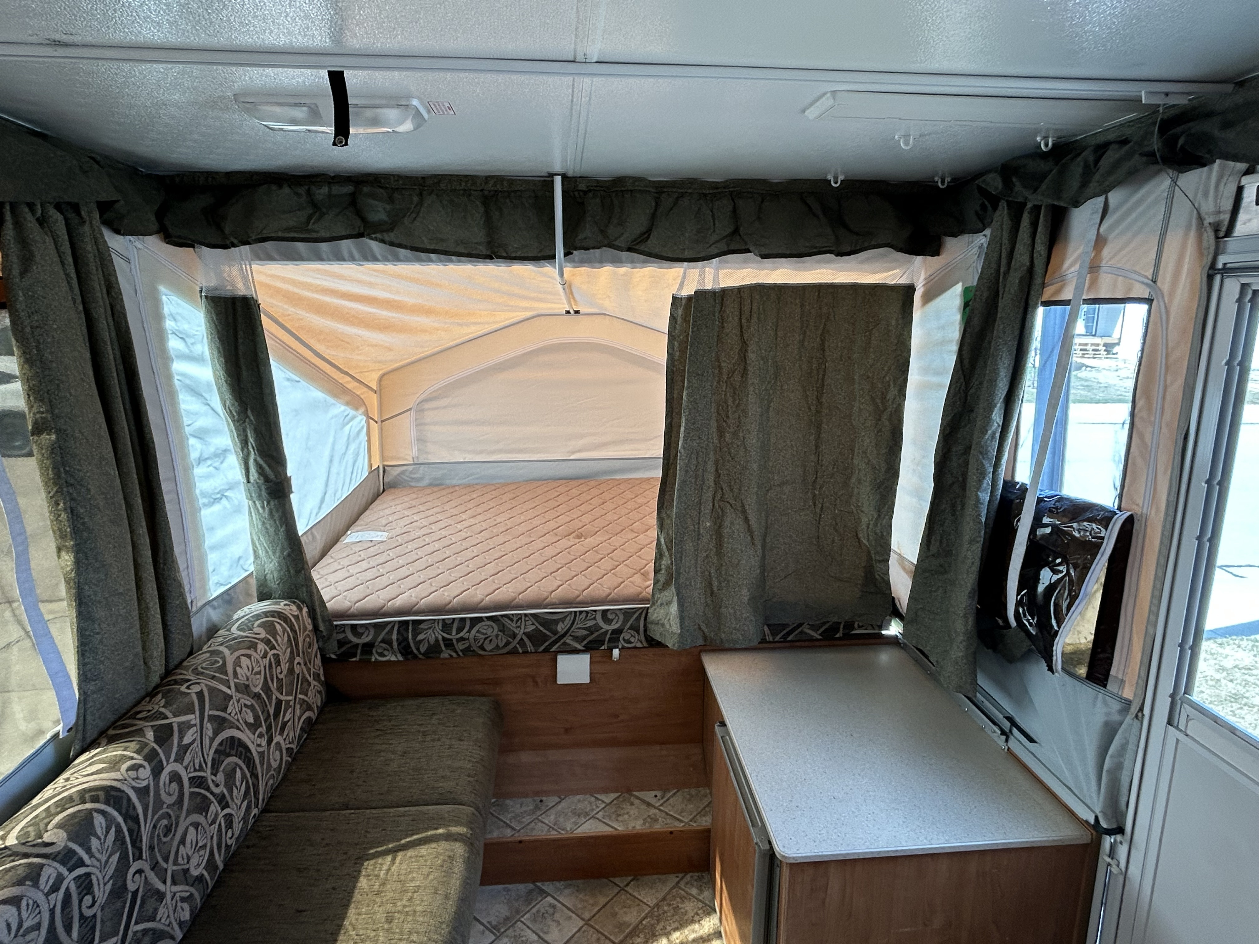 Pop-up RV rental interior: view of comfortable bed, dinette, and countertop inside this versatile camper.. Forest River Flagstaff 2008