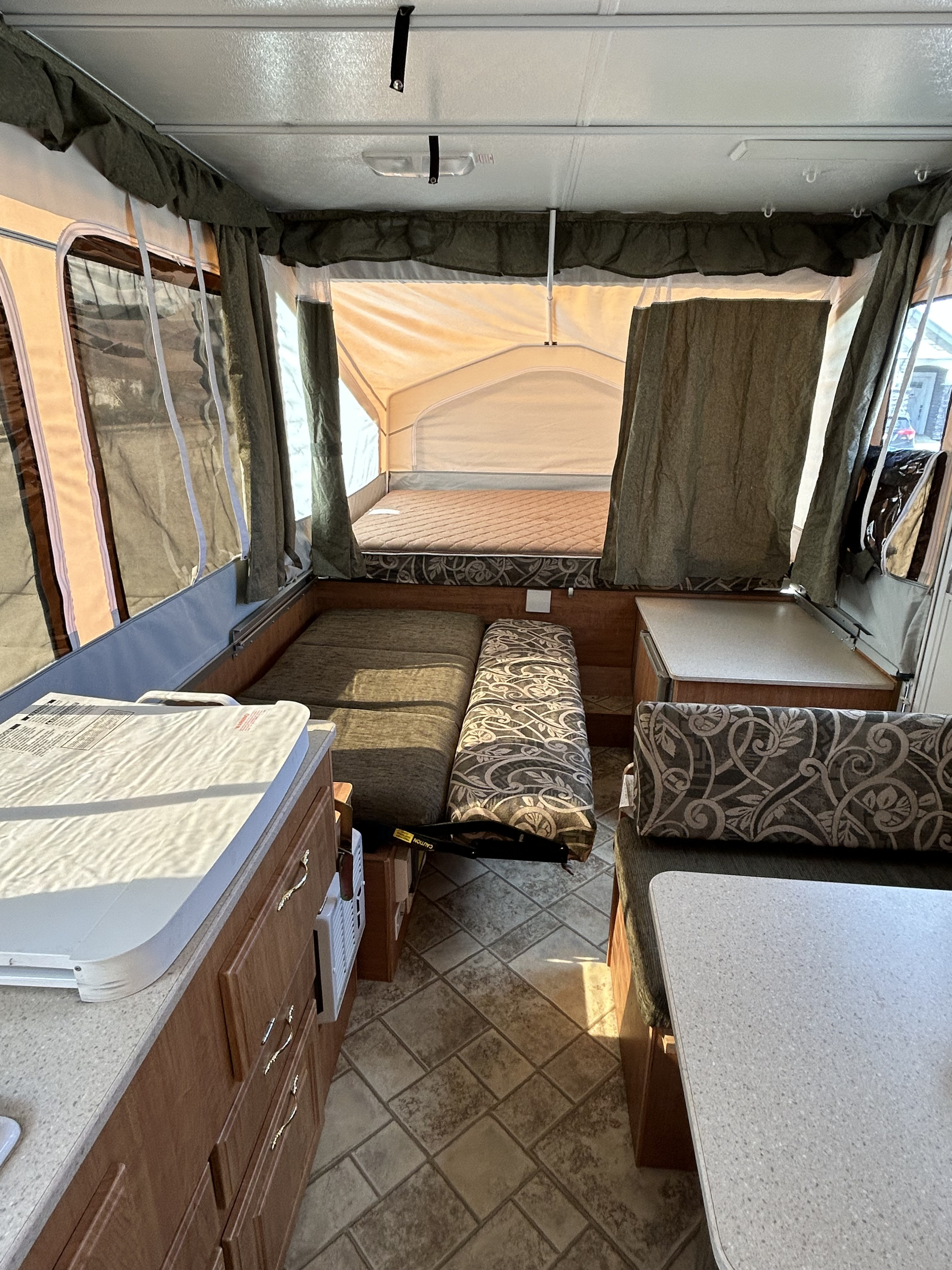 Interior of a pop-up RV rental, highlighting beds, dinette, and compact kitchen. Perfect for camping trips.. Forest River Flagstaff 2008