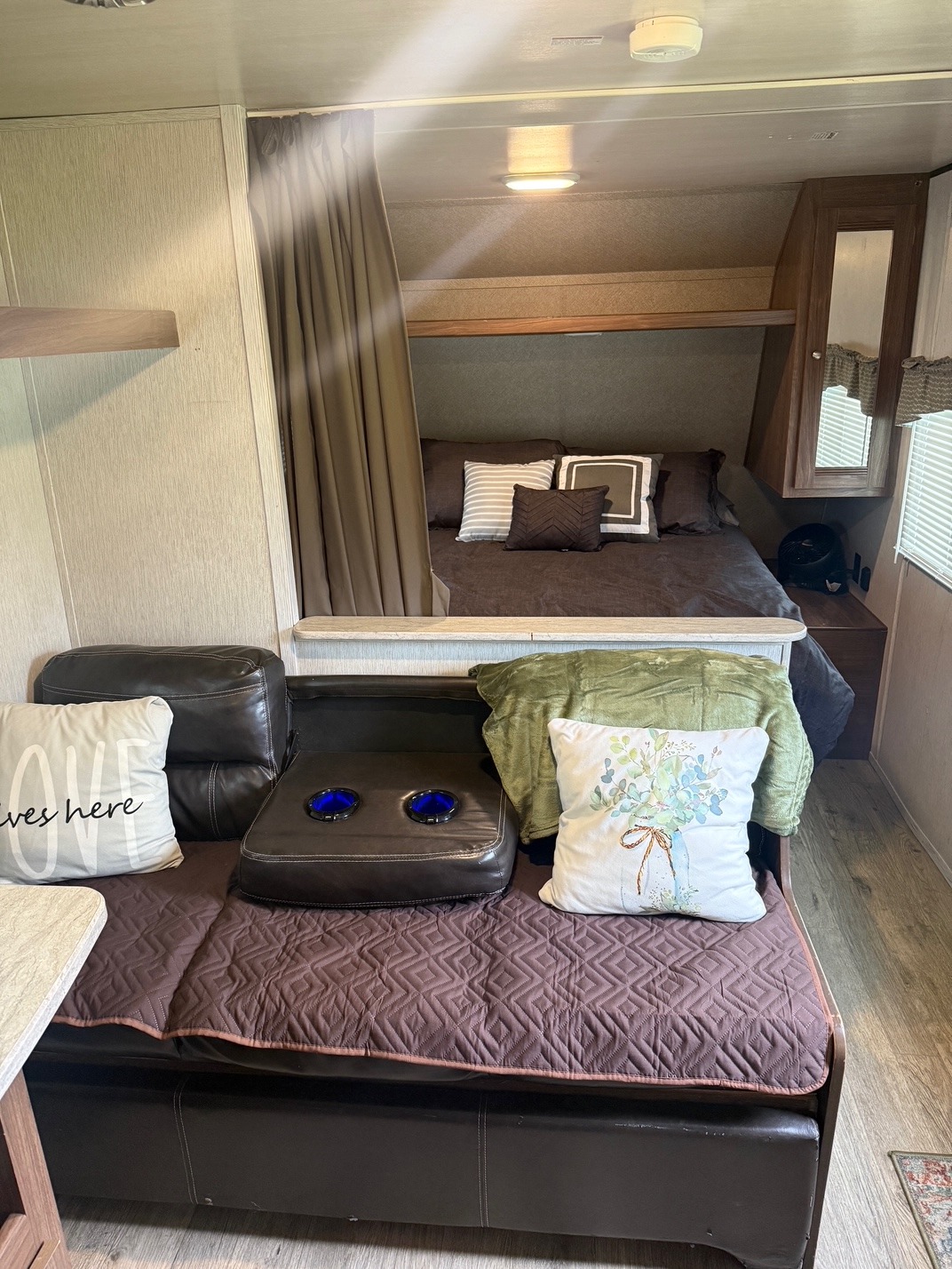 Inside a comfortable RV rental: a private sleeping area with a bed and a living space with a sofa and cushions.. Heartland RVs Prowler Lynx 2019