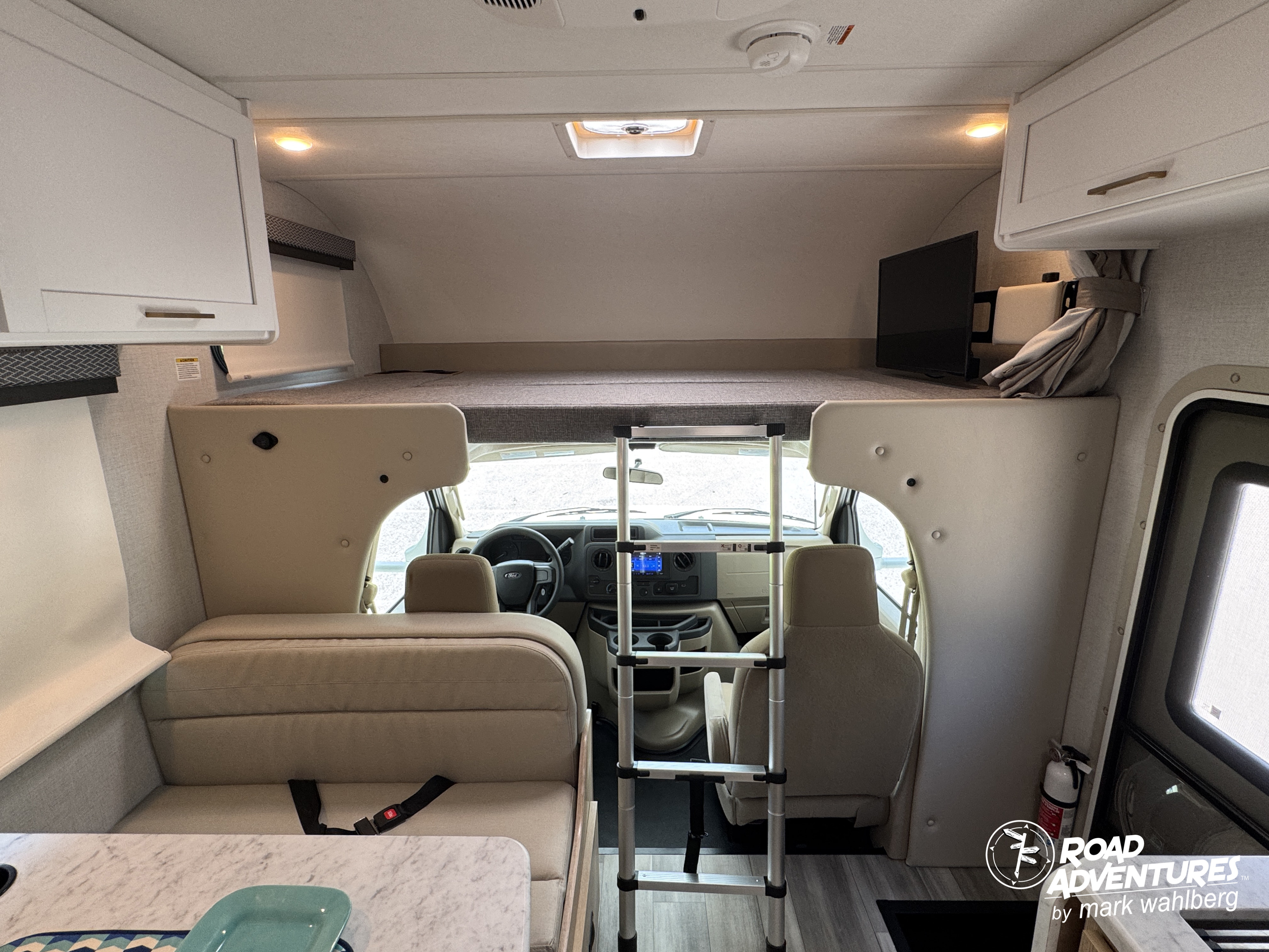 RV rental interior: Over-cab bunk with ladder, dinette seating, and driver's cabin view from the living area.. Thor Motor Coach Four Winds 2026