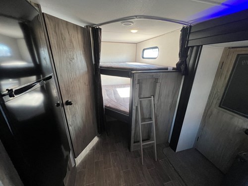 Experience comfort in this RV rental! Interior view showing a refrigerator, bunk beds with ladder, and ample storage.. Alpha Wolf 23DBH 2022