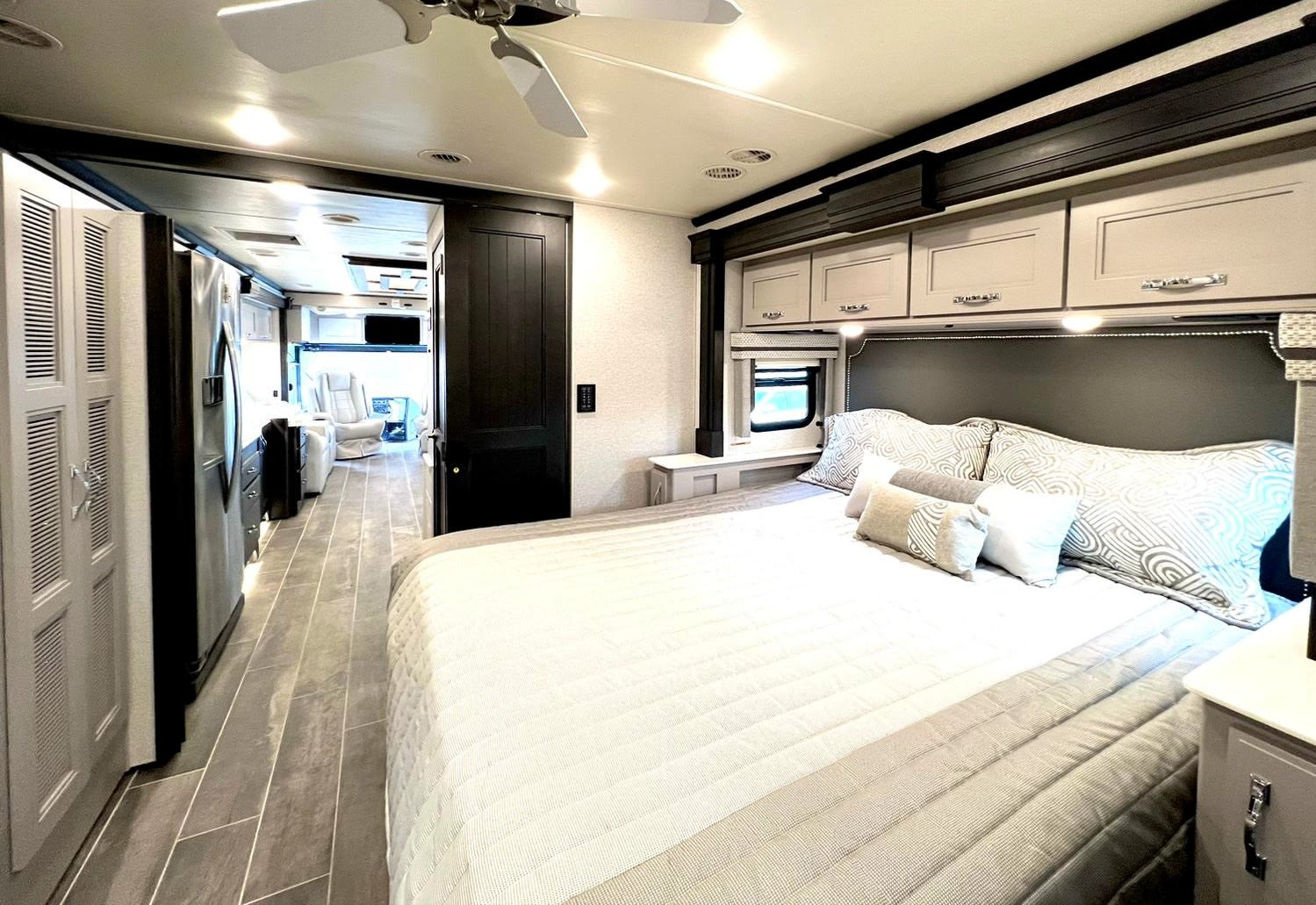 Spacious RV rental bedroom featuring a comfortable bed, overhead cabinets, and a clear view into the modern living area.. Thor Motor Coach Venetian 2023