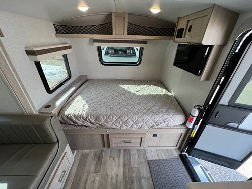 Step inside this RV rental! Features include a cozy bed, wall-mounted TV, overhead storage, and a small couch.. Rockwood GeoPro 2022