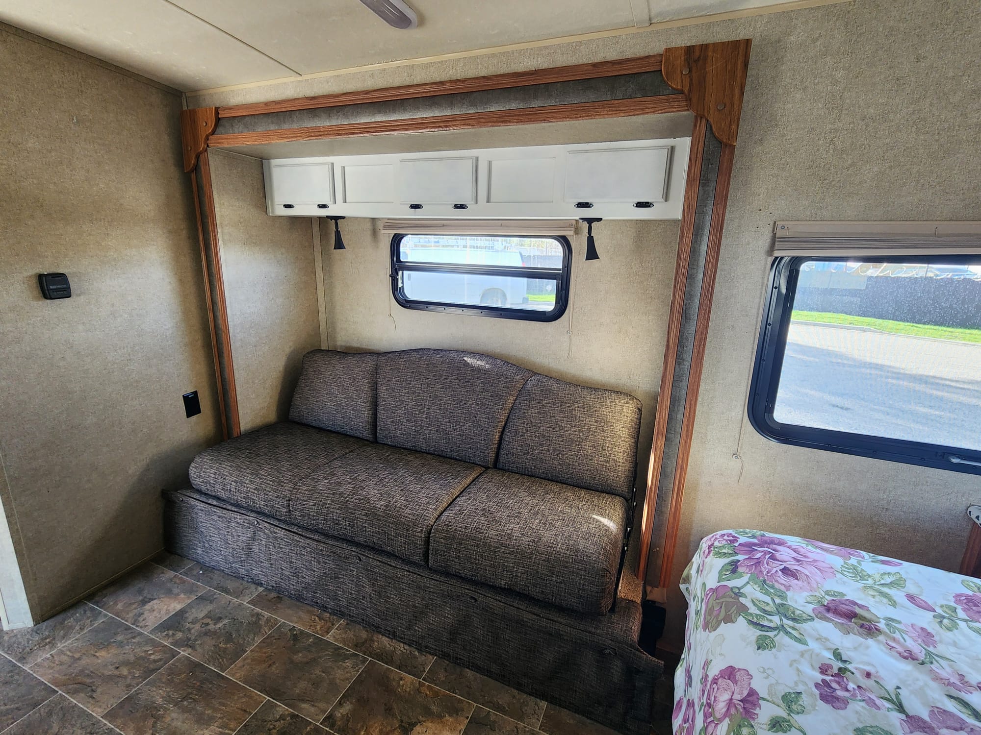 Comfortable RV rental interior with a sofa bed, overhead storage, and a cozy floral bed, ideal for travel.. Forest River Rockwood Mini Lite 2014