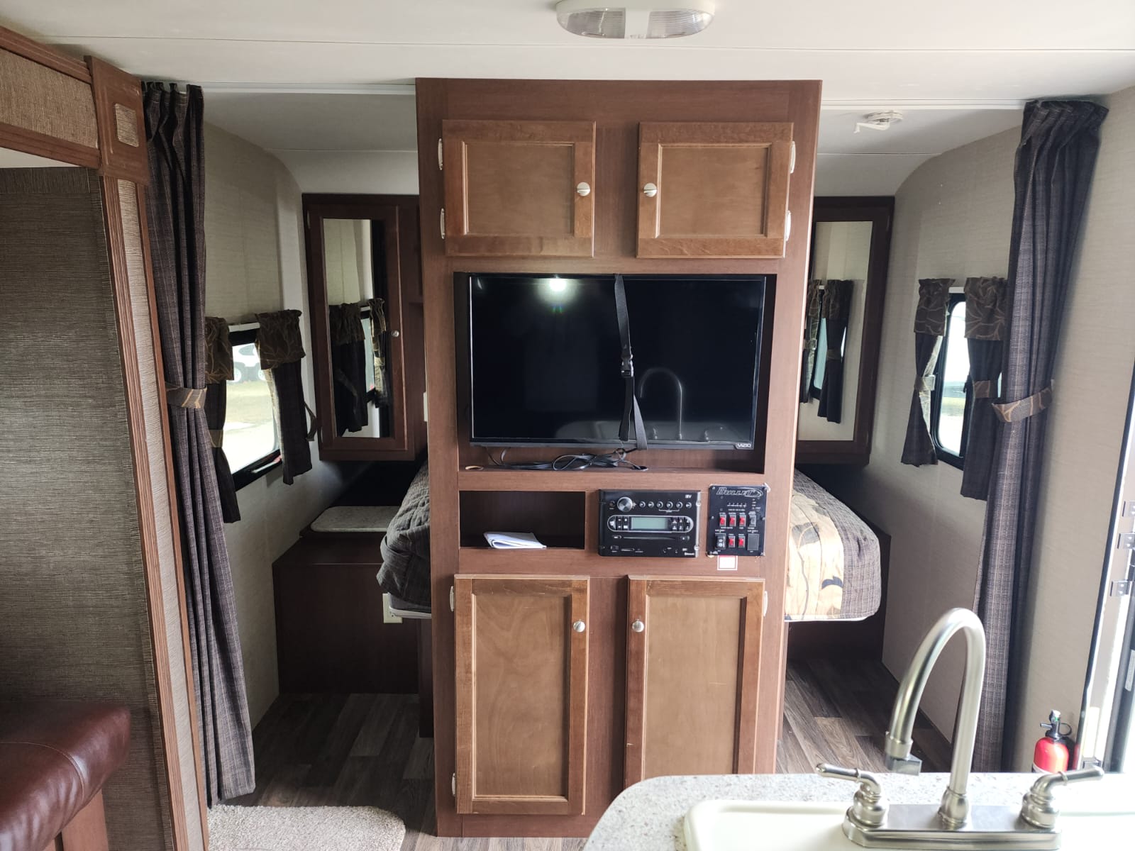 Explore this RV rental's interior: central media console, two cozy sleeping quarters, and a functional kitchen sink.. Keystone RV Bullet Ultra Lite 2015