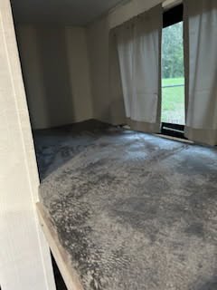 Bottom bunk bed in an RV rental, with a textured grey blanket and window curtains, ready for a cozy sleep.. Gulf Stream Ameri-lite 2024