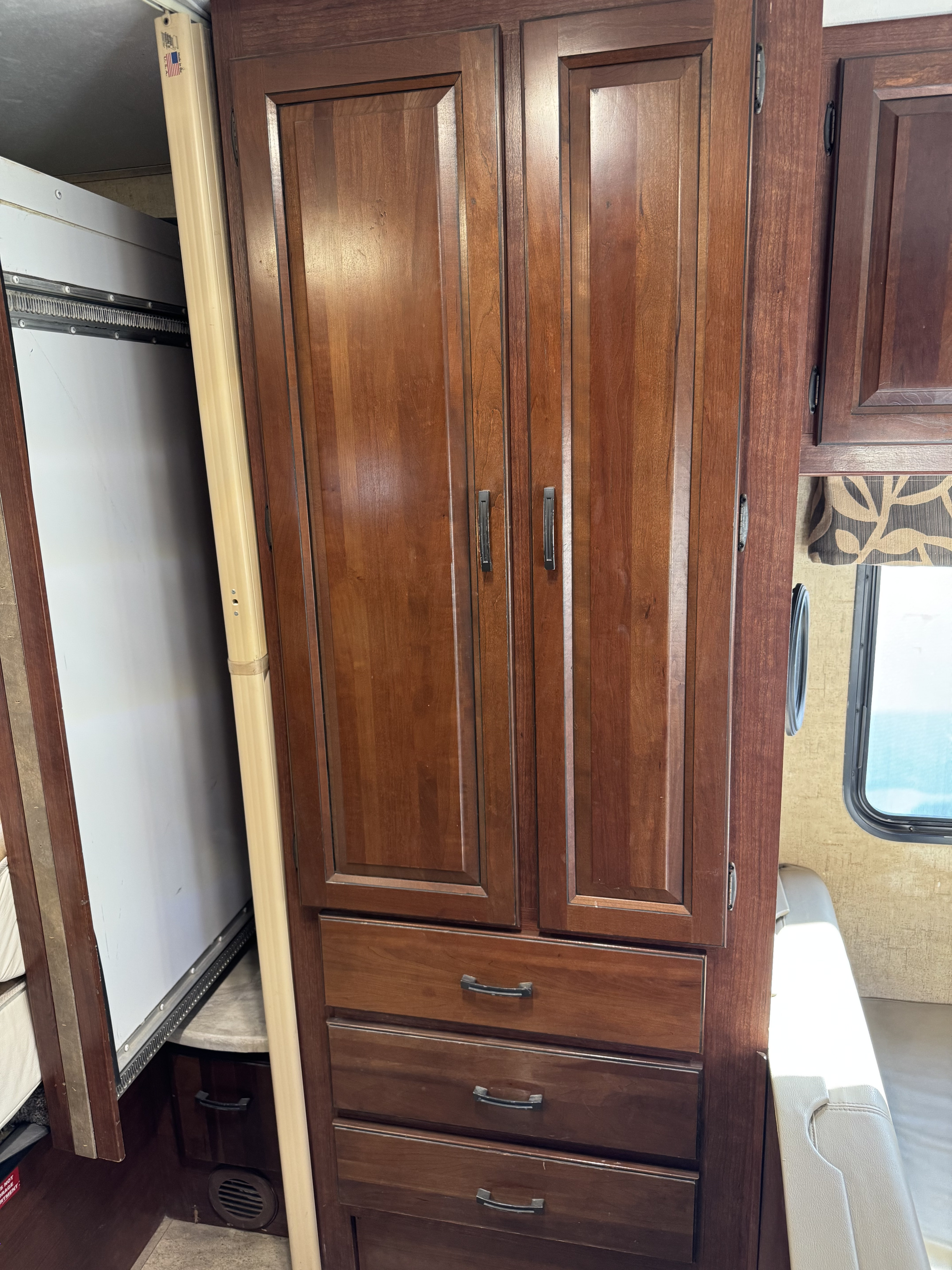 RV rental interior: Detailed dark wood storage cabinets with drawers, adjacent to a beige slide-out expansion and a window.. Forester LE 2016