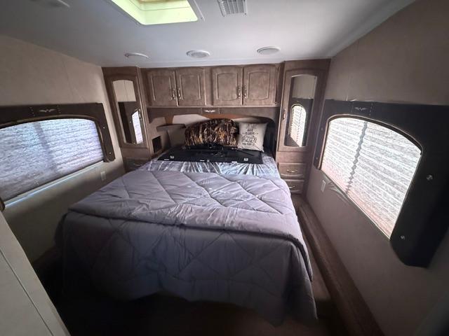 RV rental bedroom featuring a large bed with grey bedding, wooden overhead cabinets, and two windows with blinds.. Weekend Warrior 3505 Le 2008